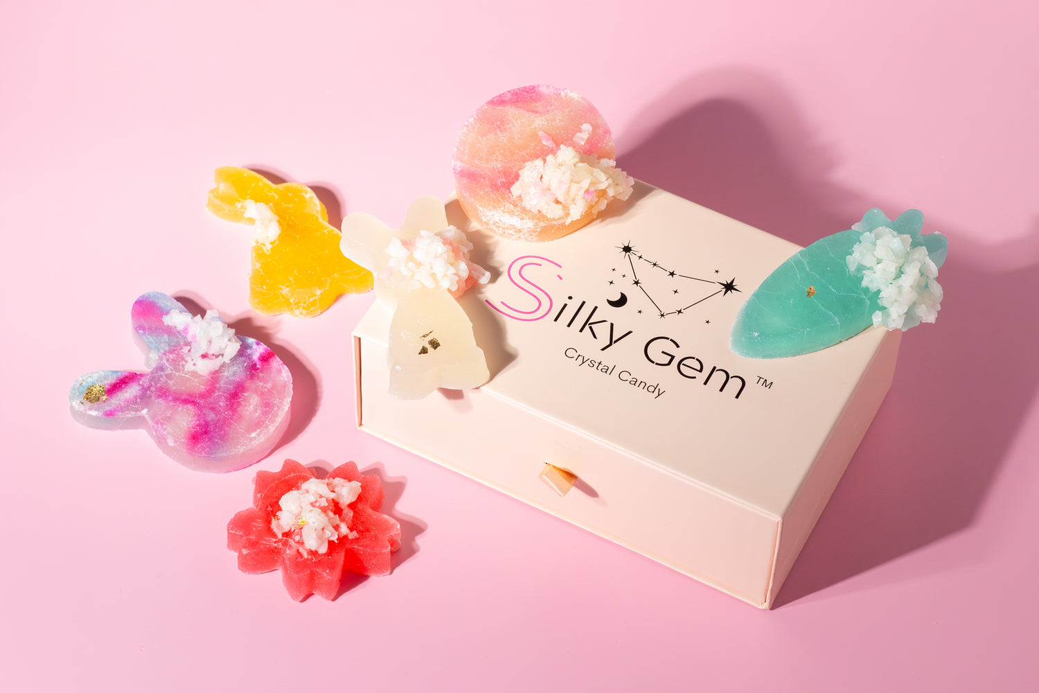silky gem's crystal candy surrounding a branded pink box. The candy is shaped in signature easter kohakutou shapes, a carrot, bunny and flower crystal candy