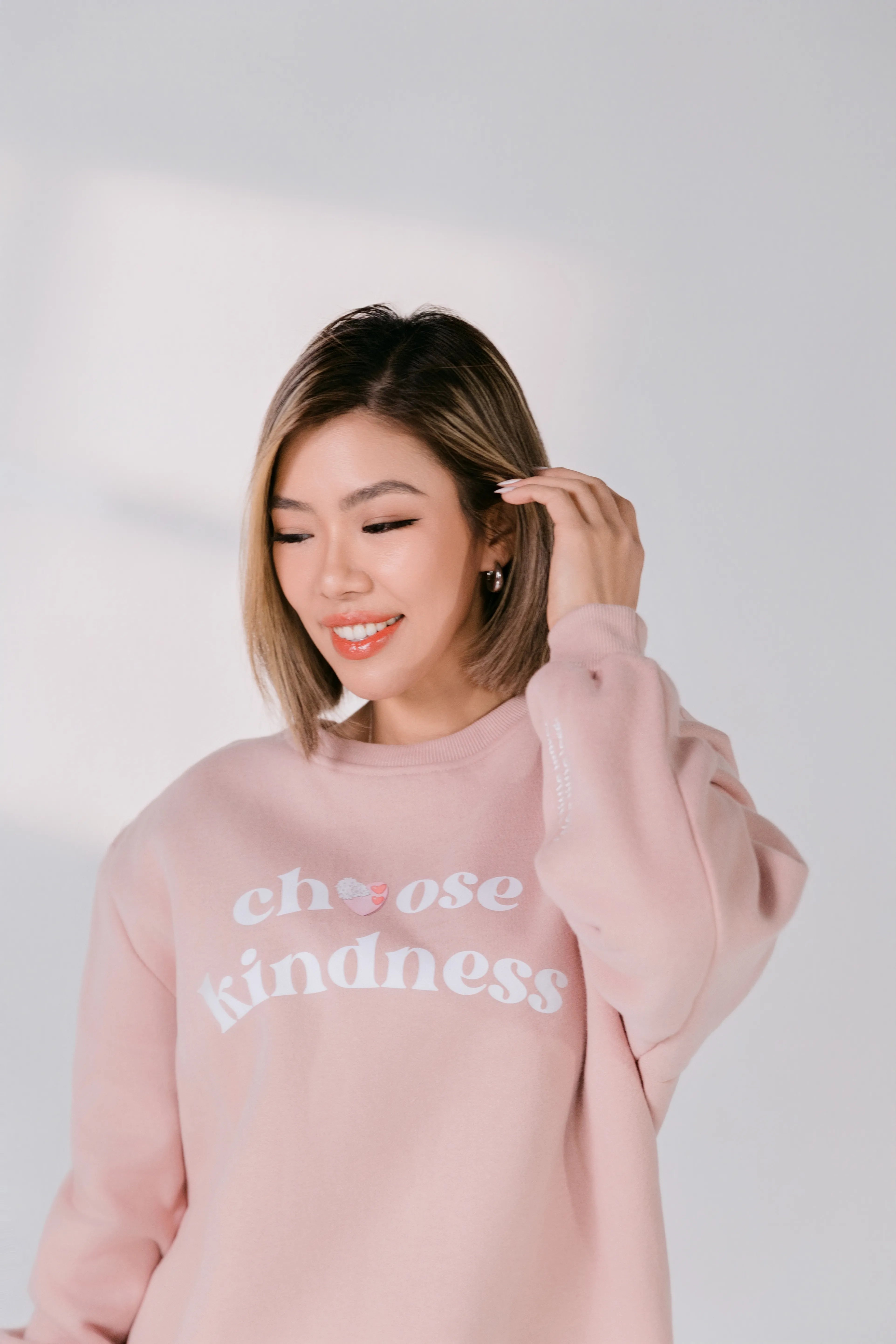 Model wearing blush pink “Choose Kindness” Silky Gem crewneck sweatshirt, front view.