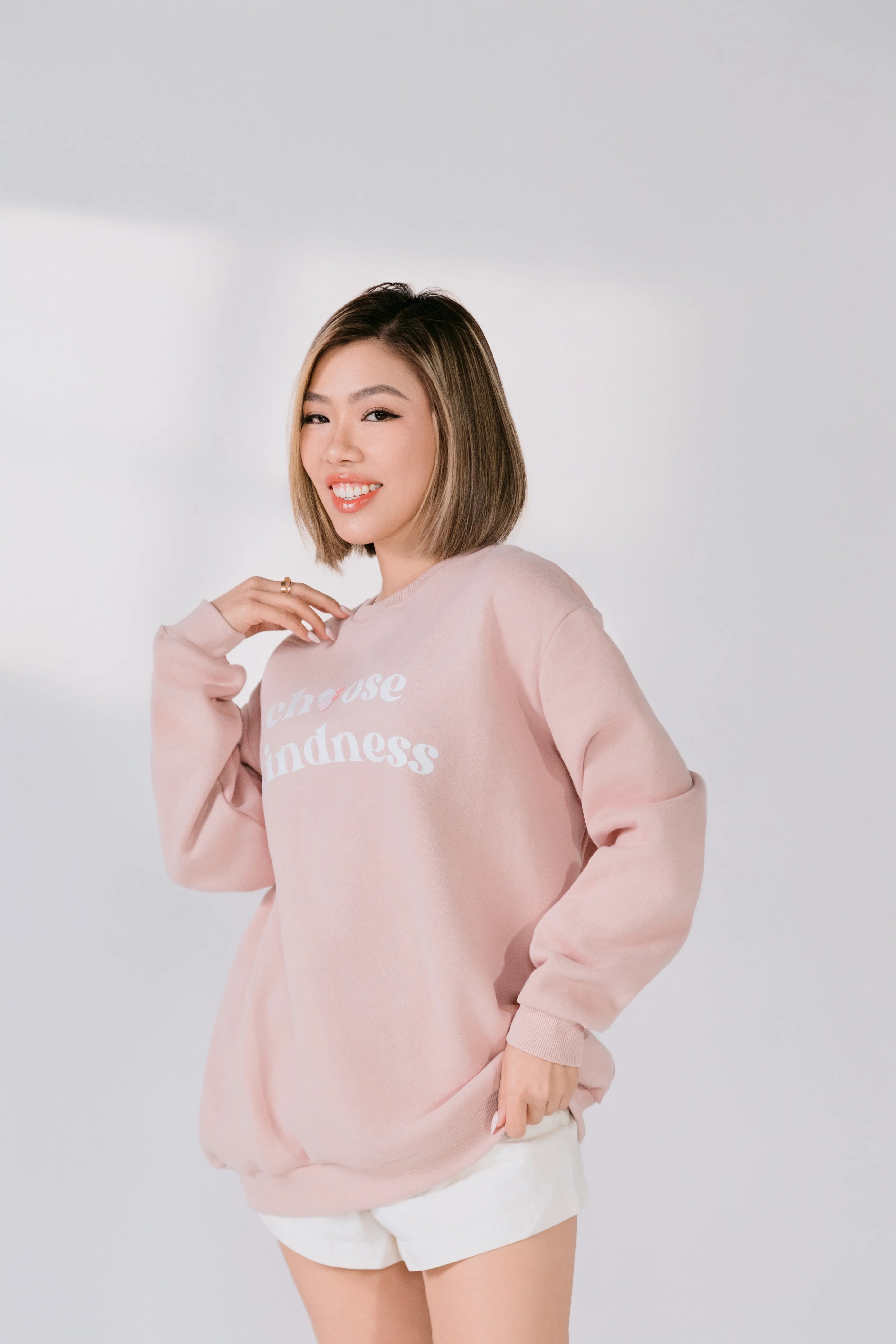 Woman wearing a pink sweatshirt with text on a plain background