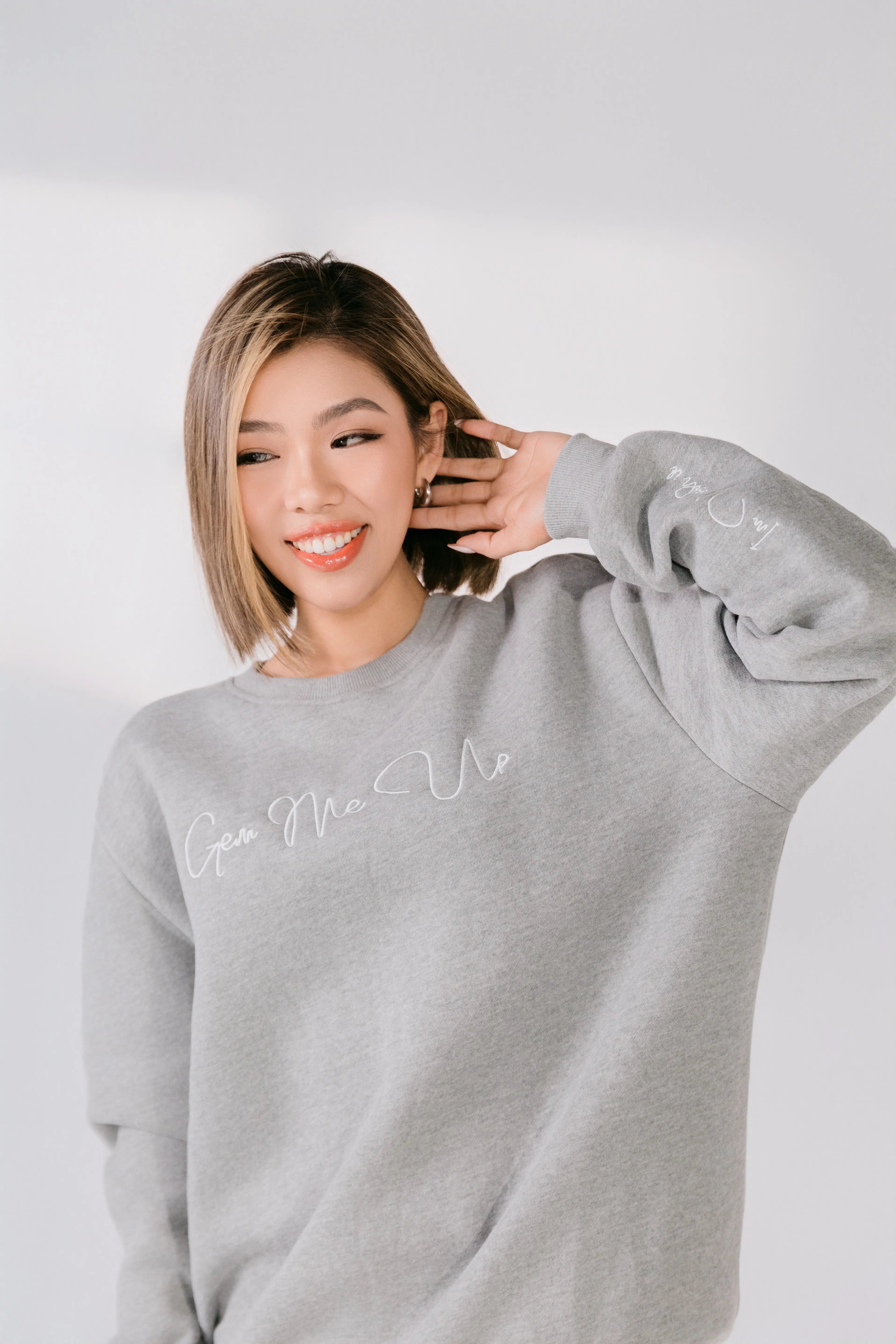 Woman wearing a gray sweatshirt with text on a plain background