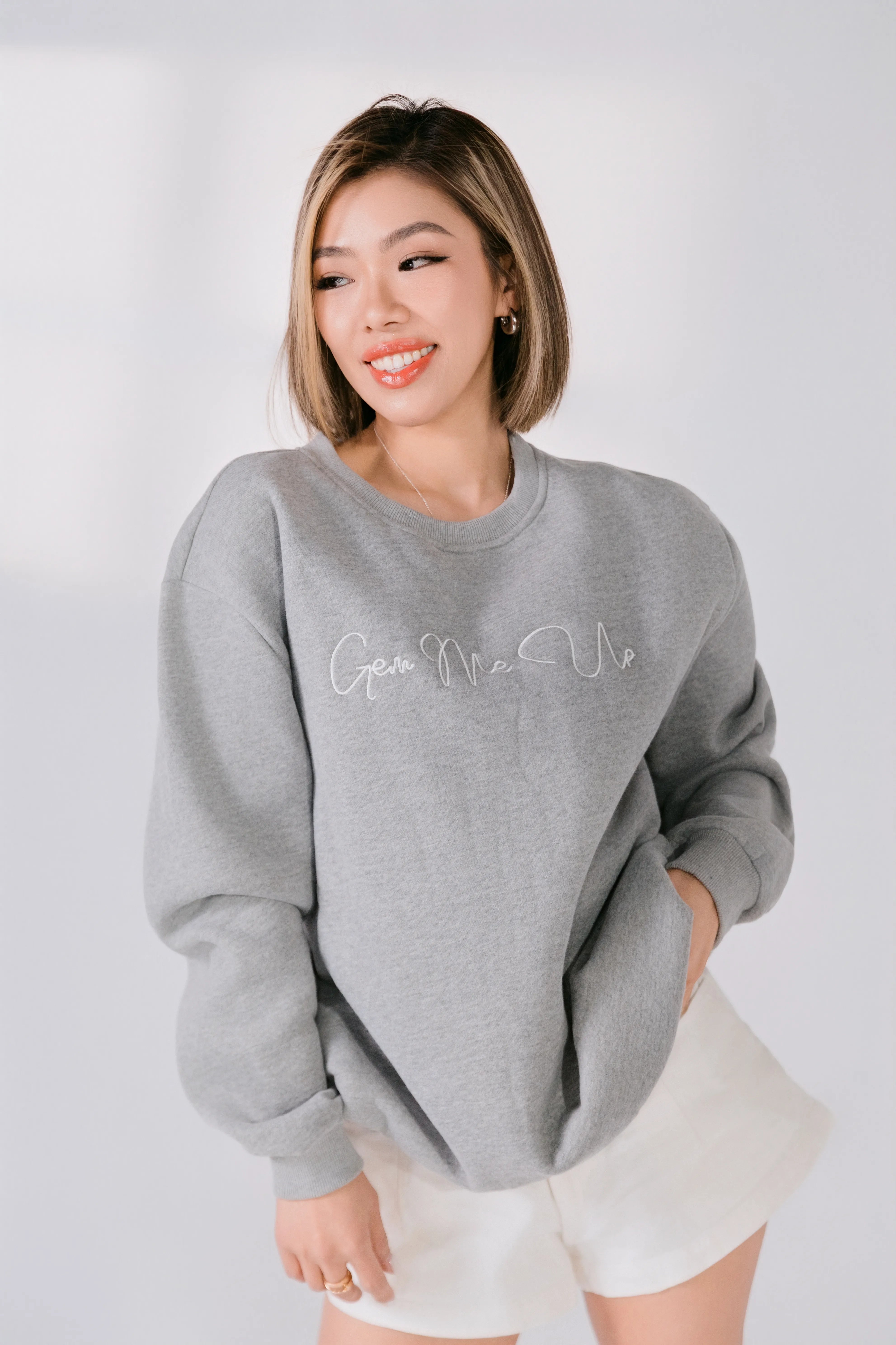Woman wearing a gray sweatshirt with text on a white background