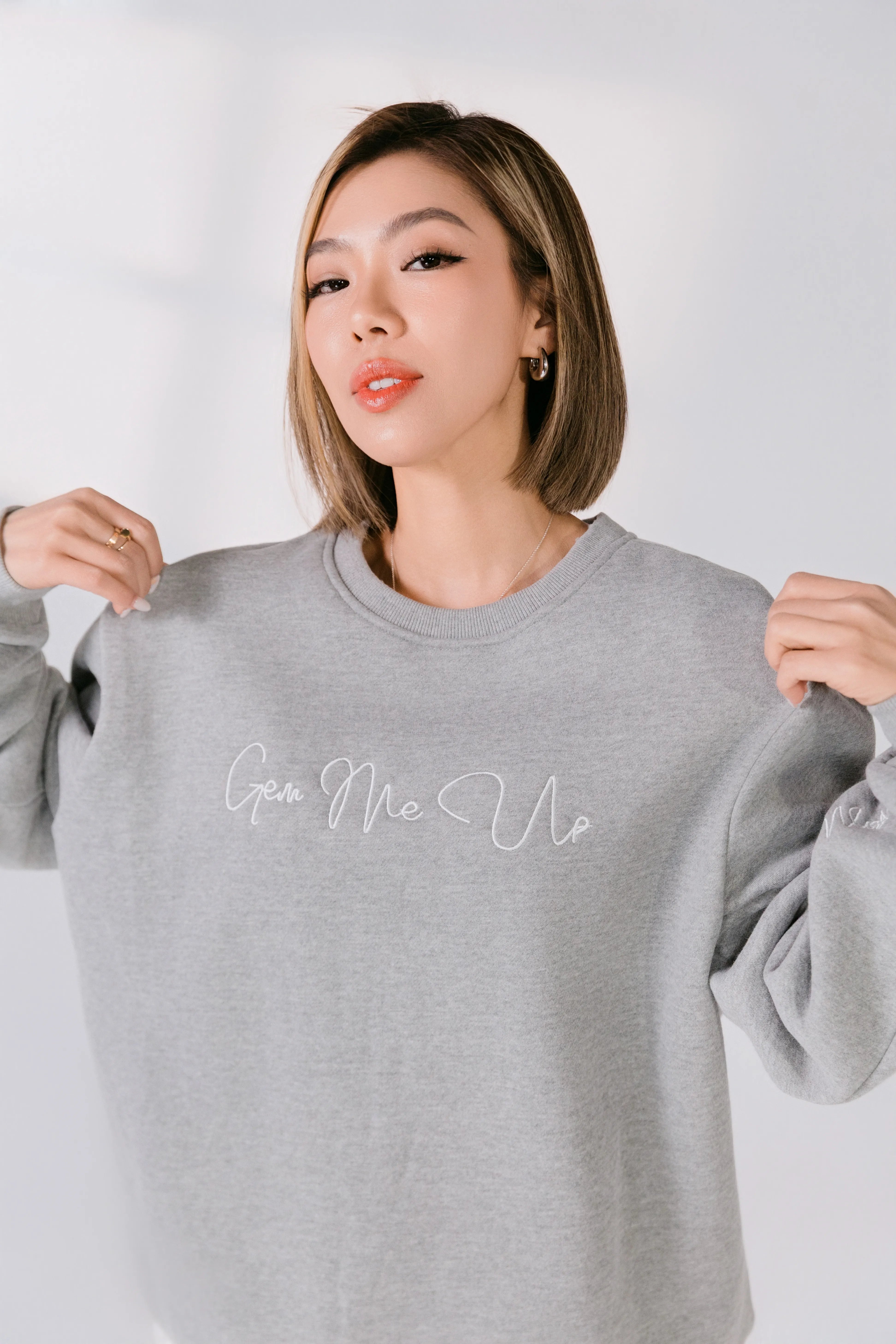 Woman wearing a gray sweatshirt with text on a plain background