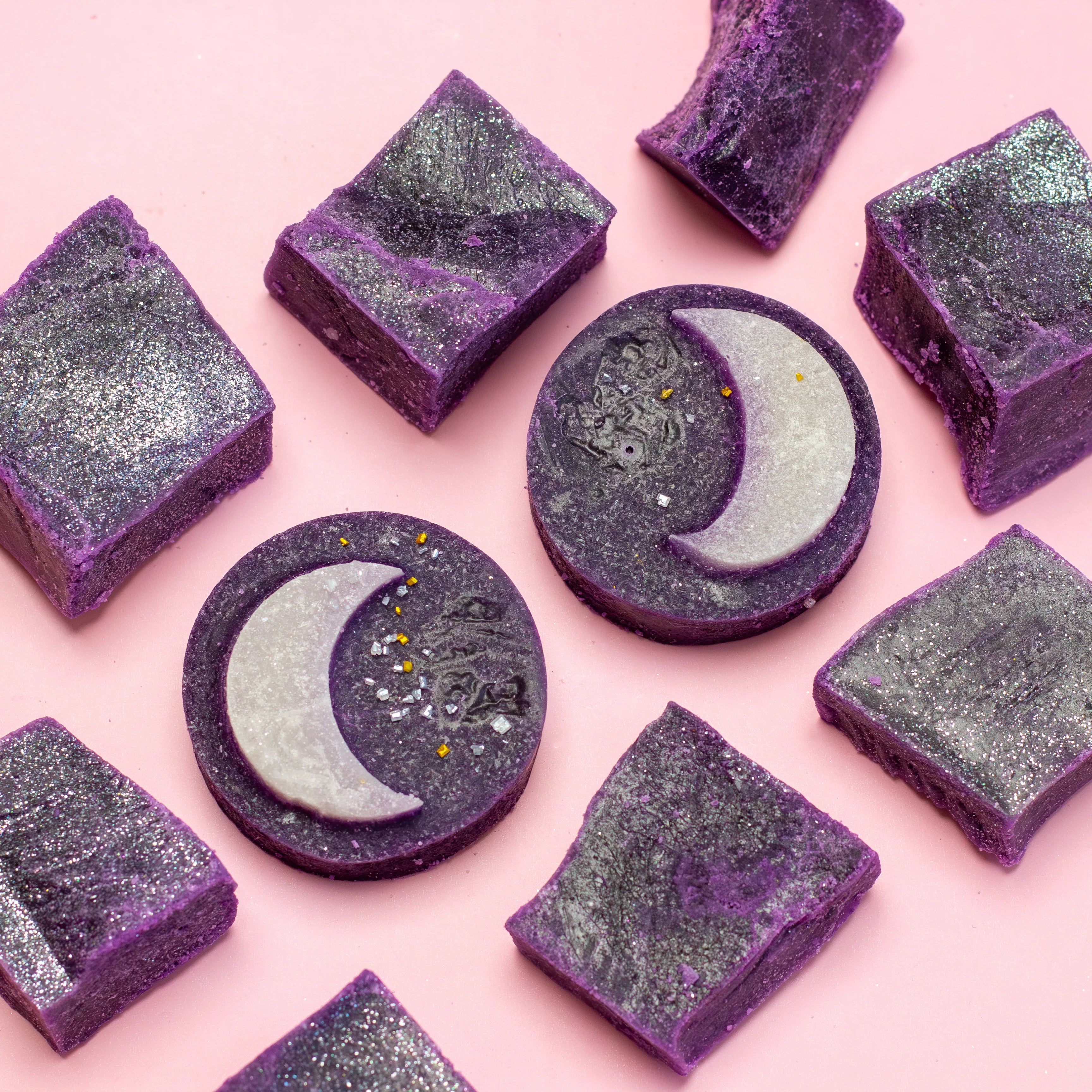Purple and gray soap bars with a moon design on a pink background