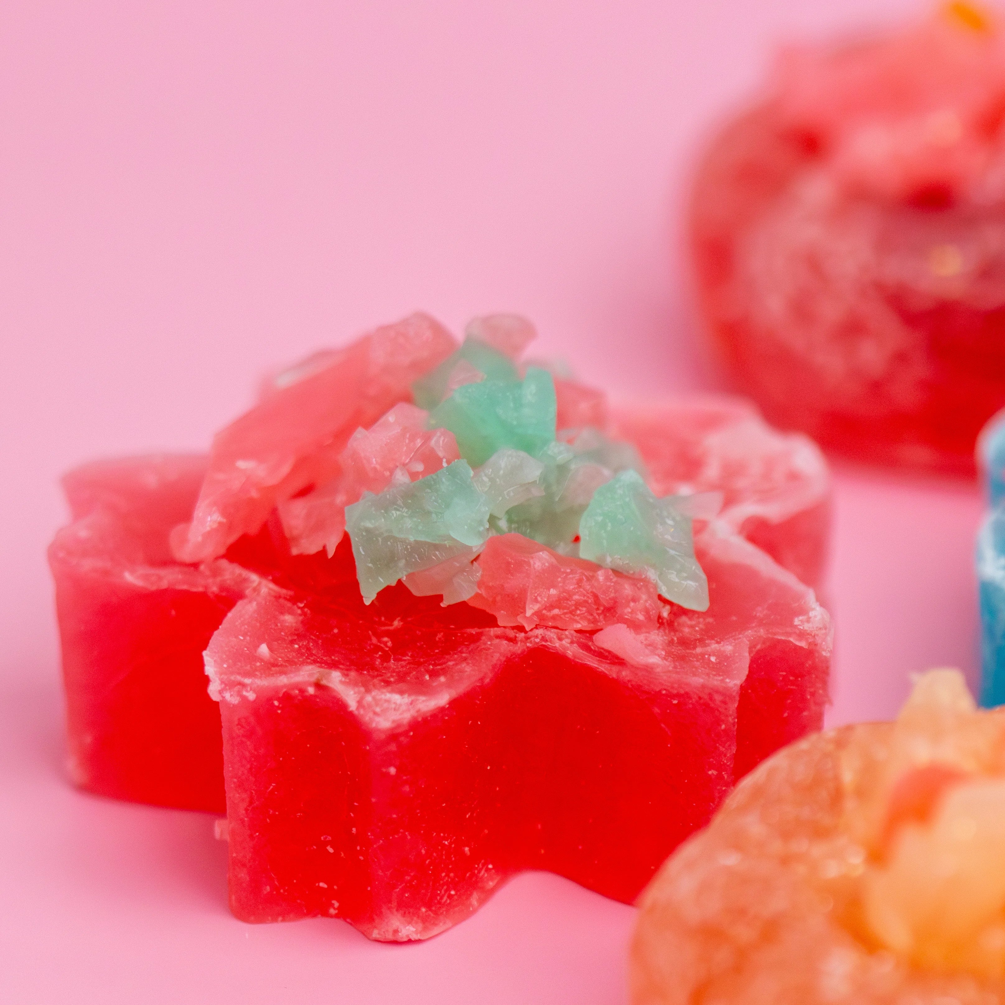 Red and green gummy candy on a pink background