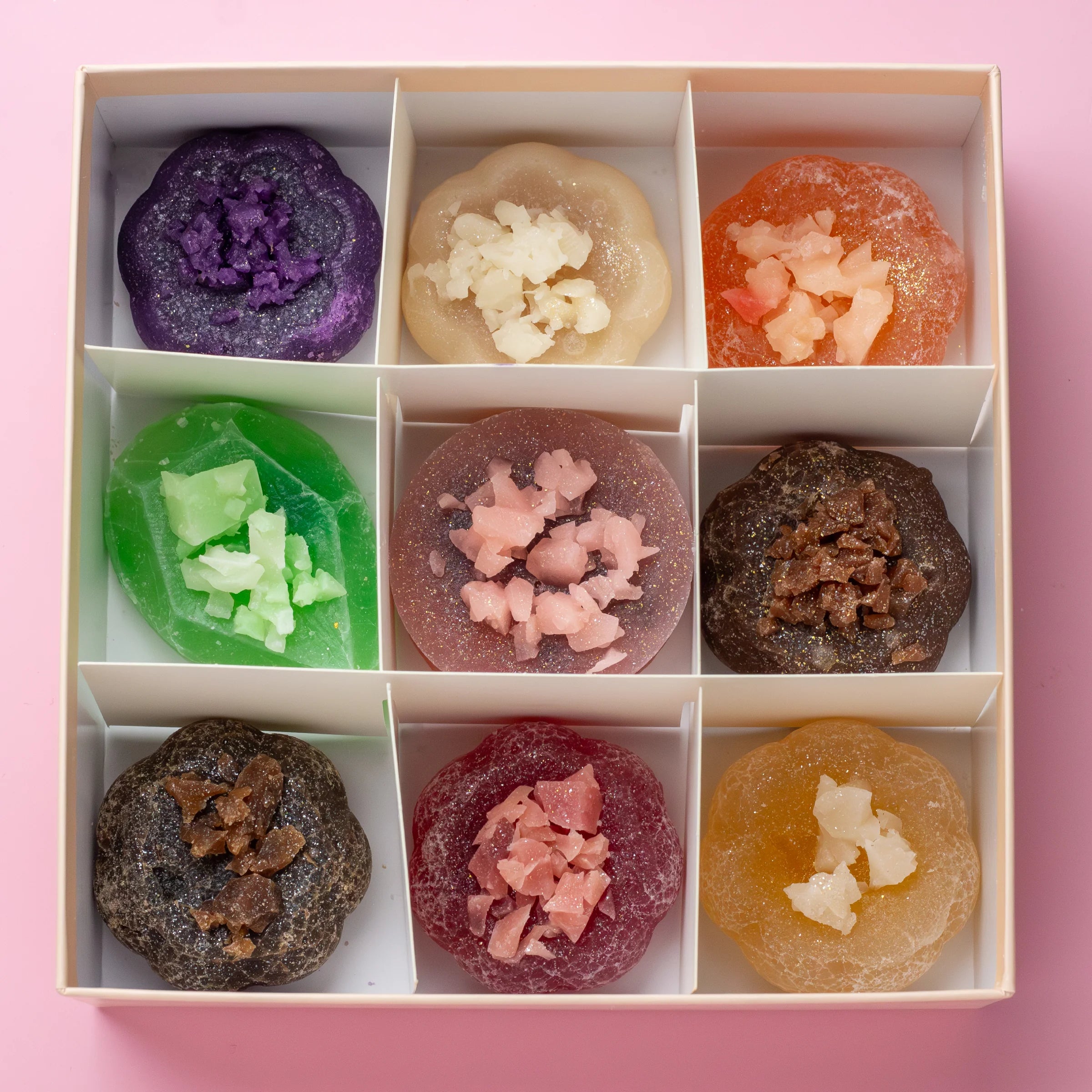 Assorted jelly candies in a box on a pink background