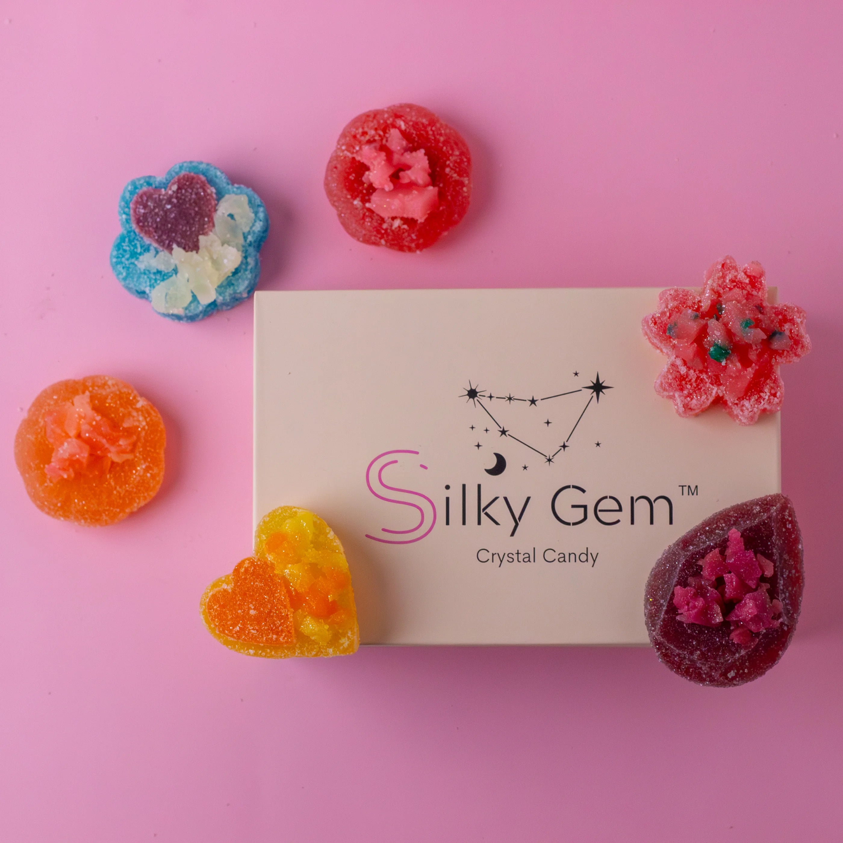 Colorful gummy candies with 'Silky Gem' branding on a pink background
