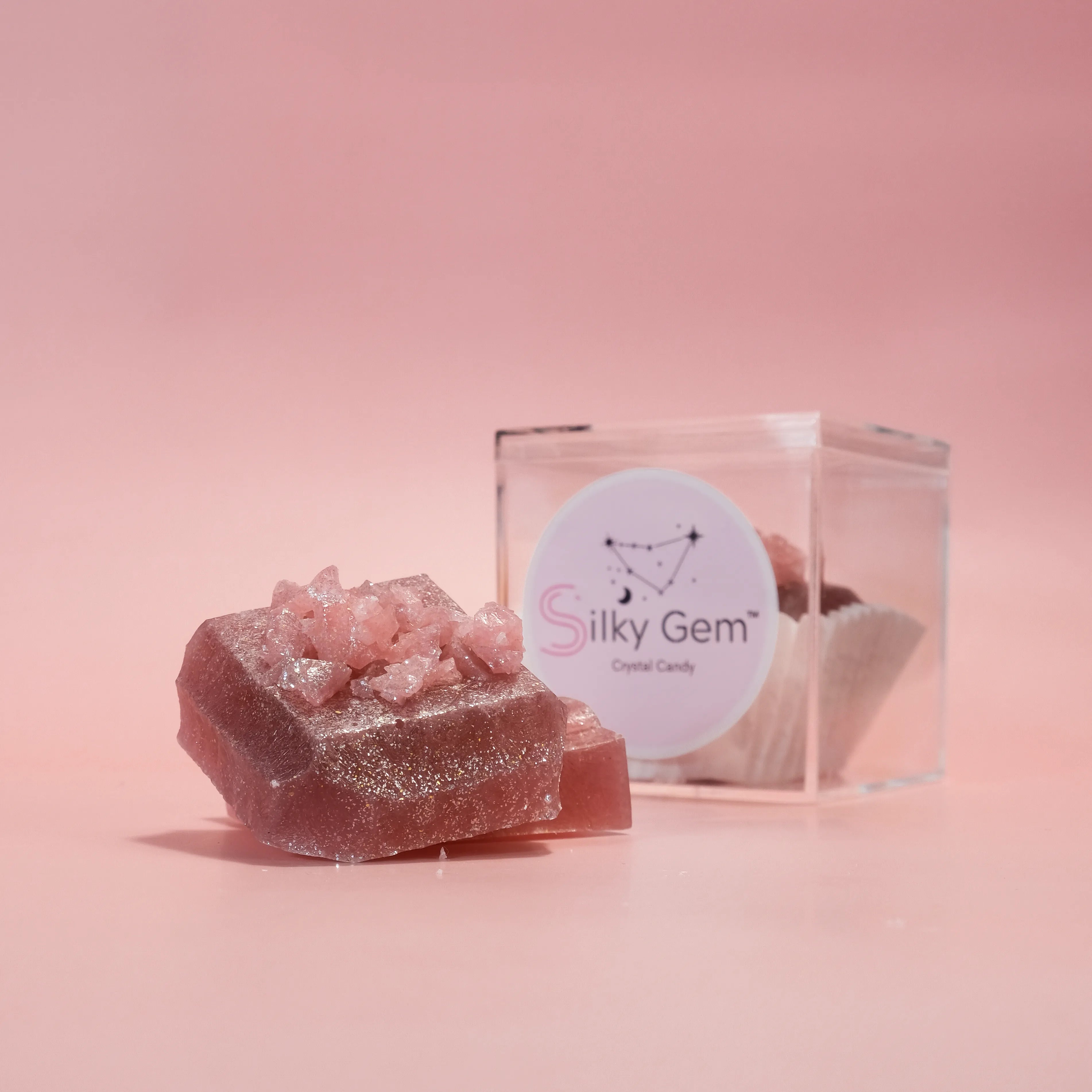 Handcrafted Silky Gem crystal candy displayed in a clear gift box on a soft pink background, featuring sparkling sugar crystals and jewel-like texture.