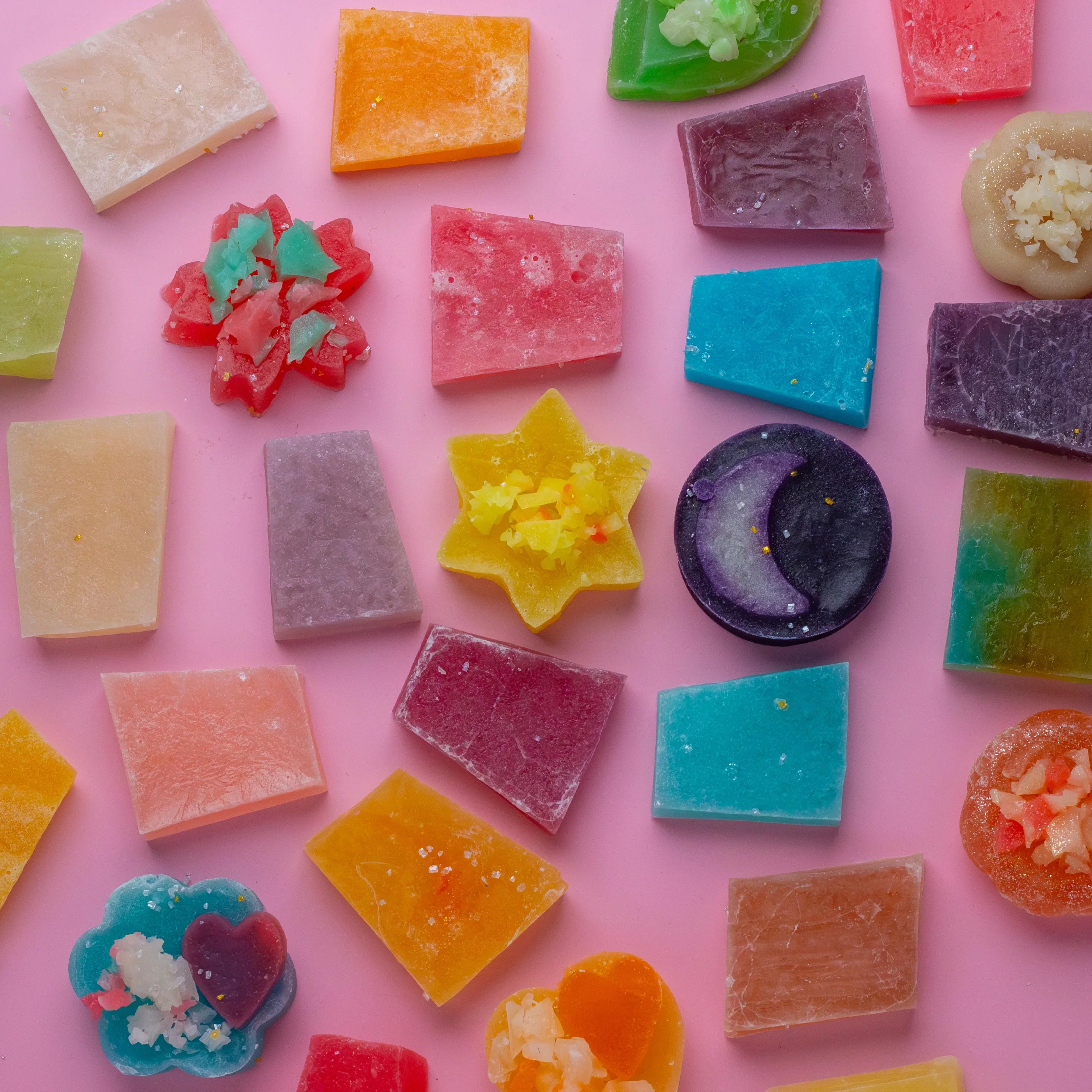 Assorted colorful gummy candies on a pink background