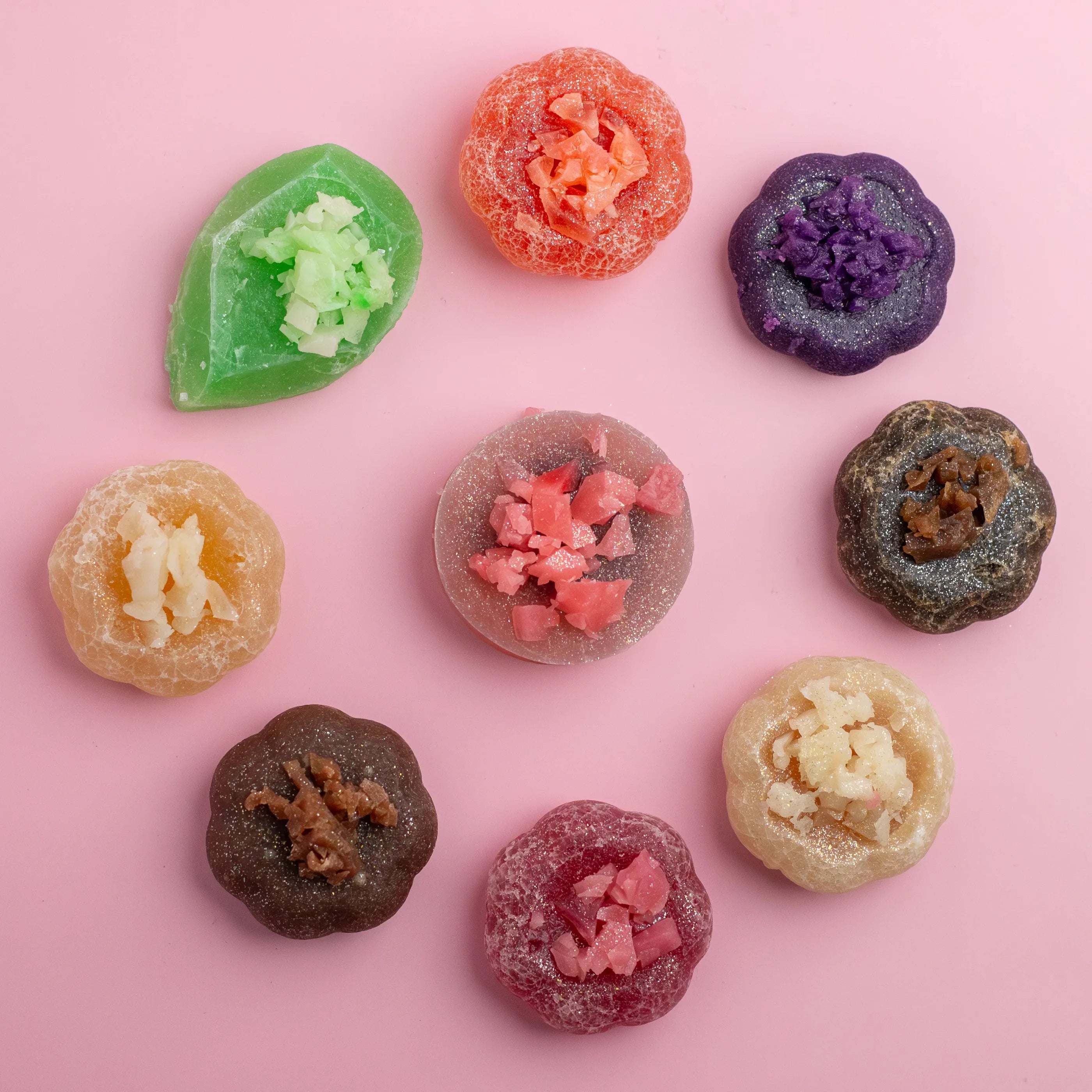 Assorted colorful gummy candies on a pink background