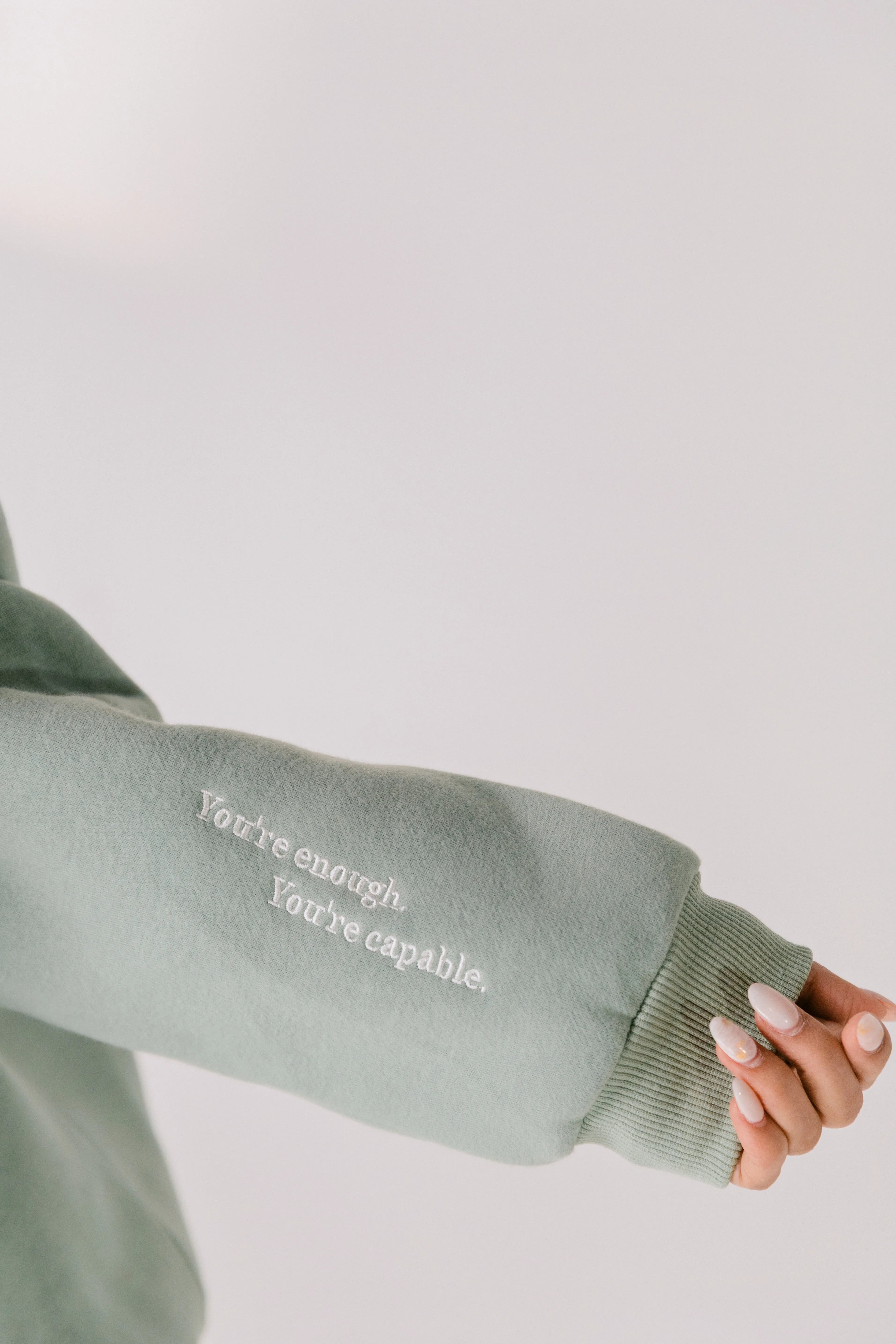Close-up of sleeve embroidery reading “You’re enough. You’re capable.”
