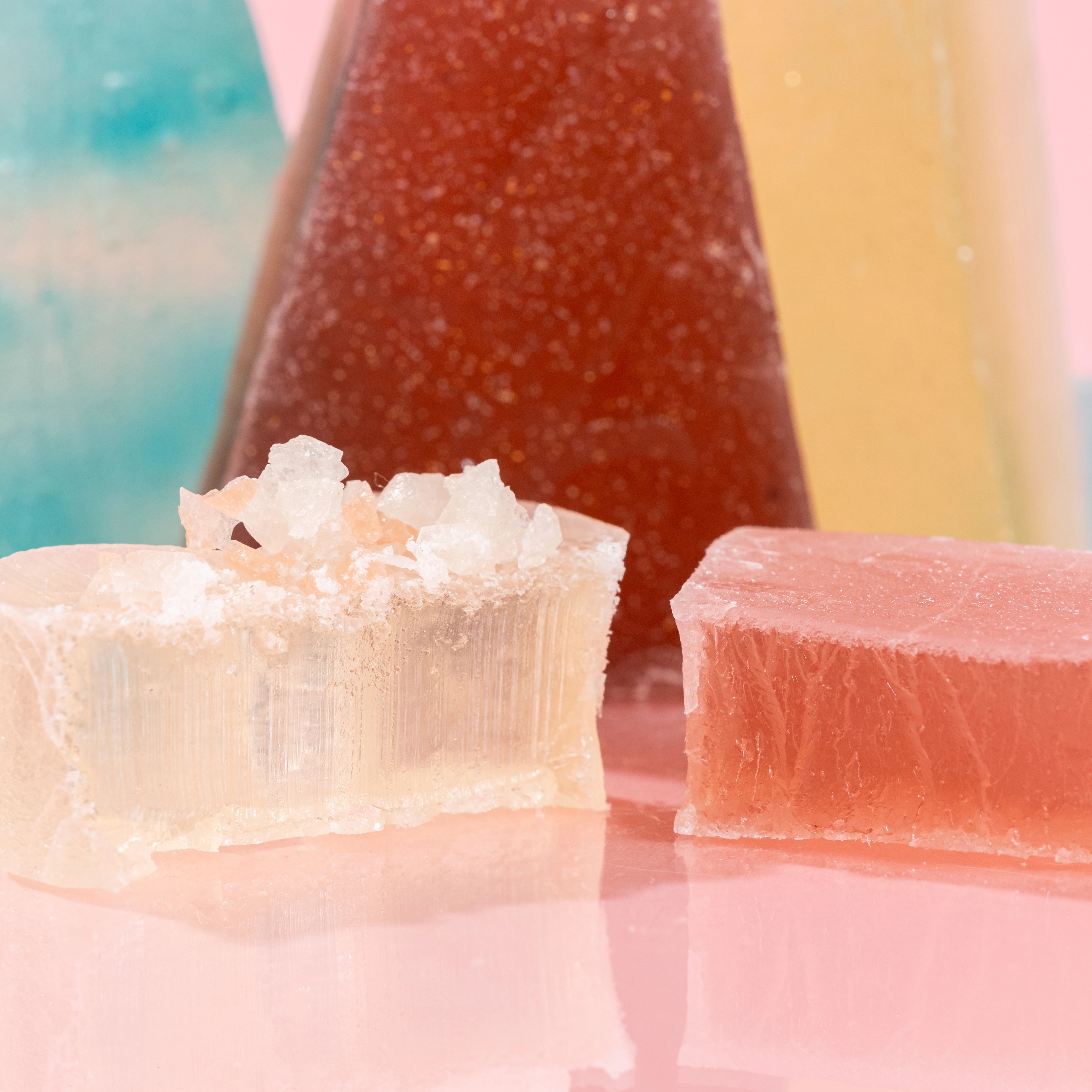 Close-up of a cut-open Silky Gem crystal candy revealing the firm, jelly-like center on a pink background.