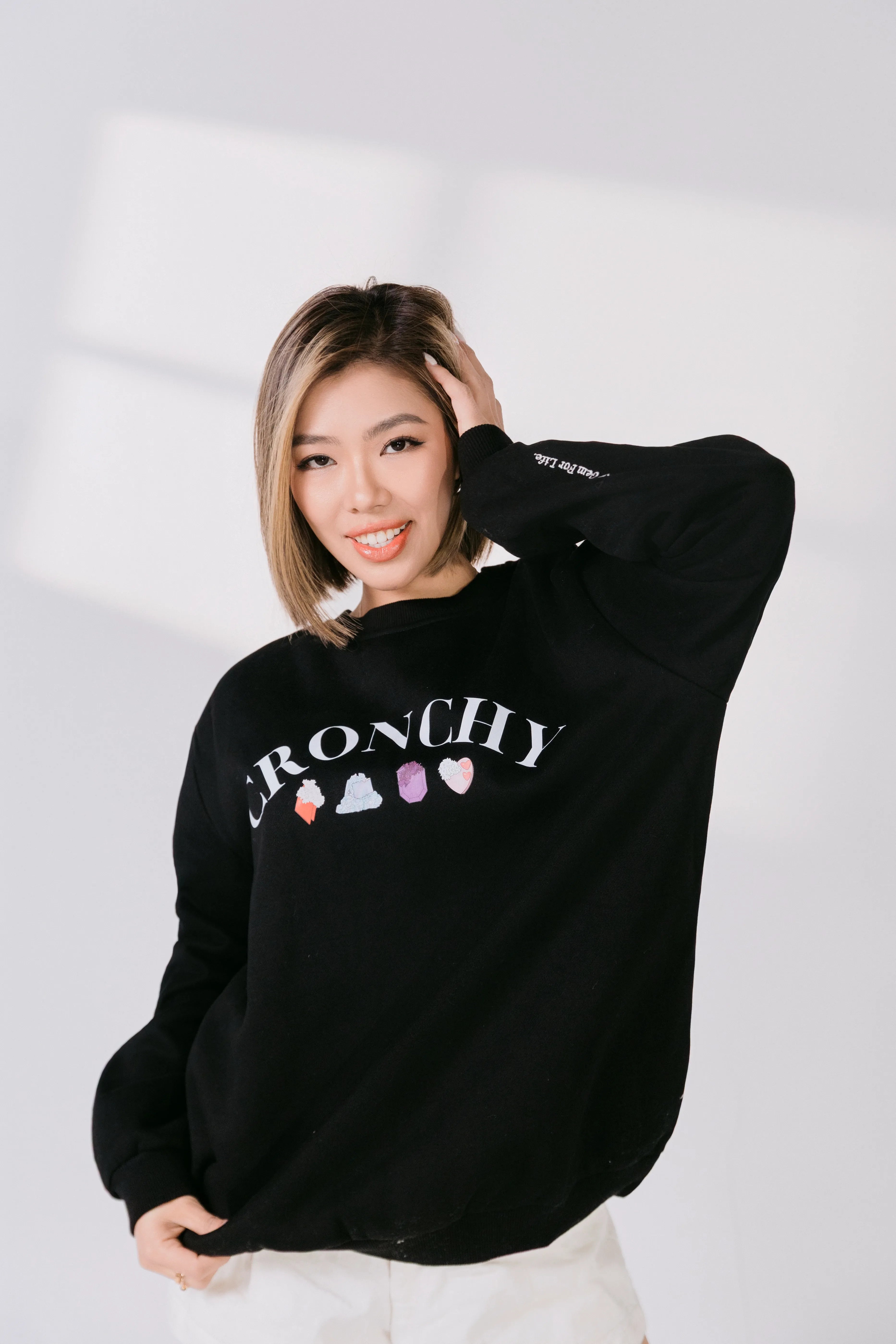 Three-quarter view of black CRONCHY graphic crewneck styled casually.