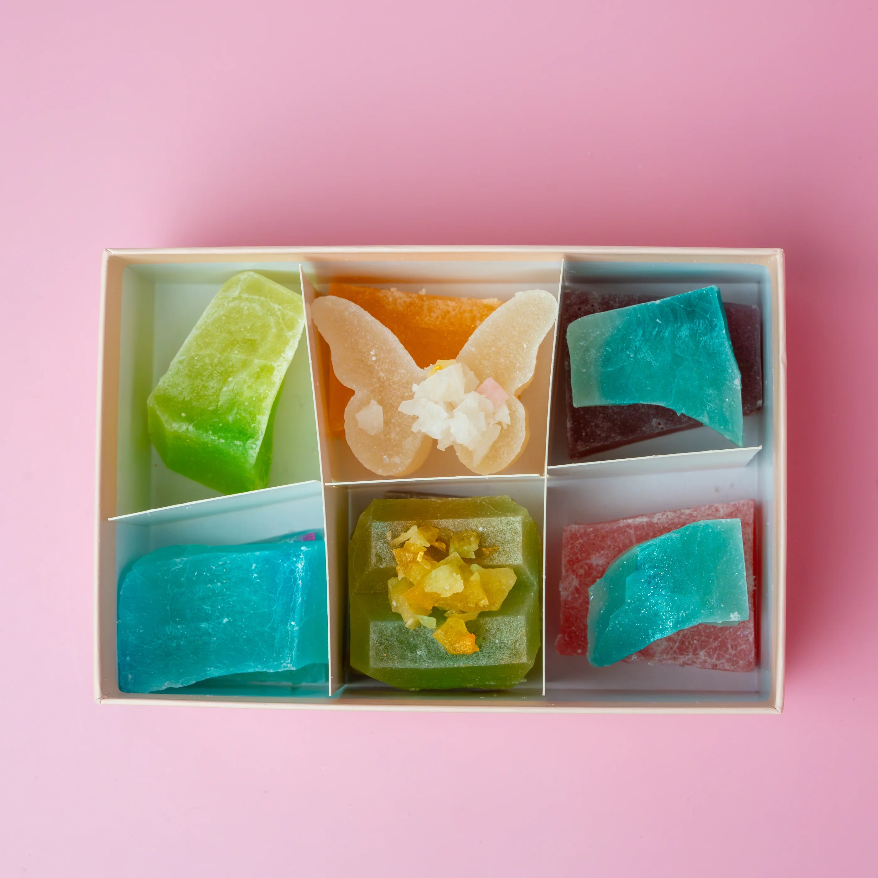 Colorful soap bars in a box on a pink background