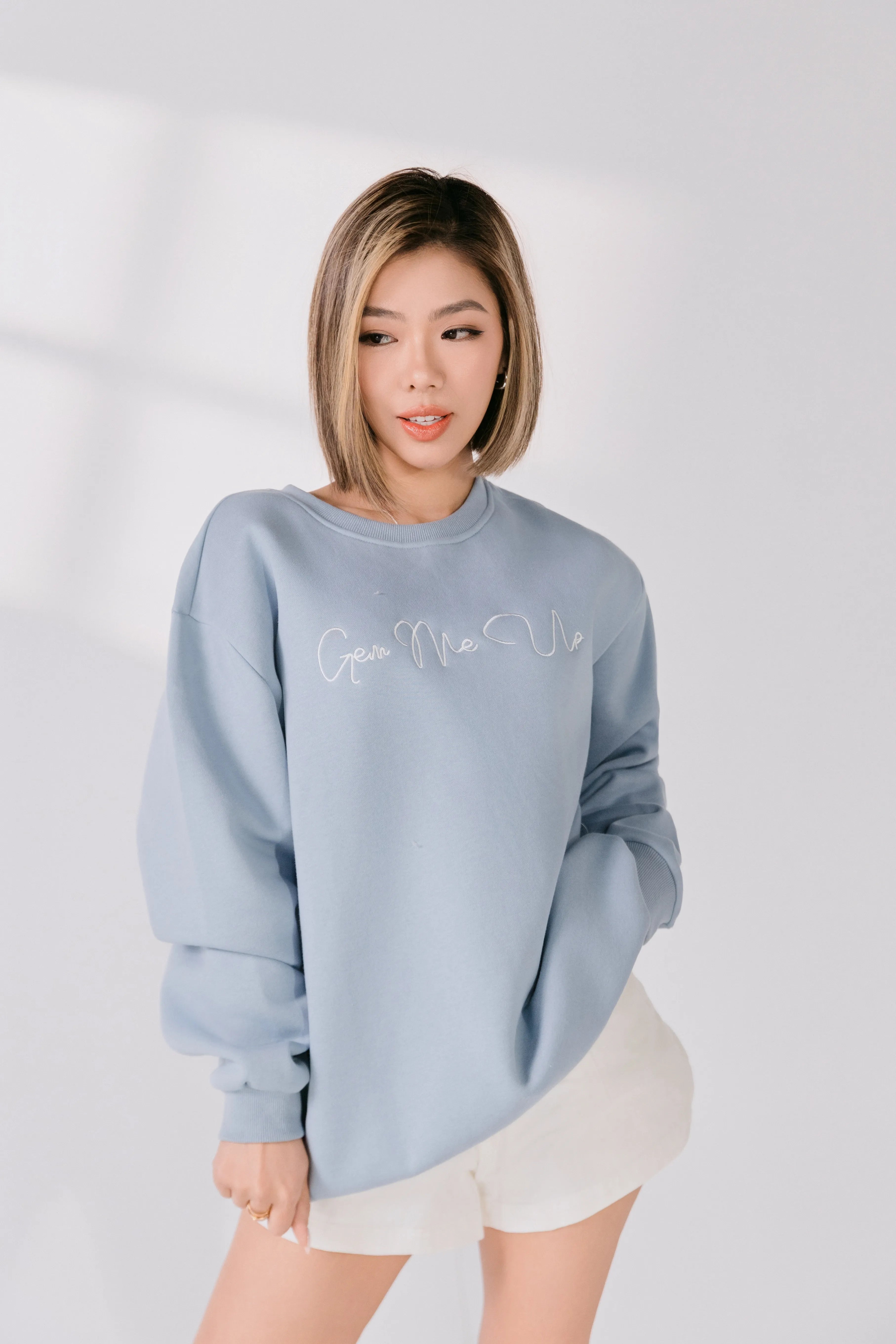 Front view of powder blue cotton poly blend crewneck with embroidered text.