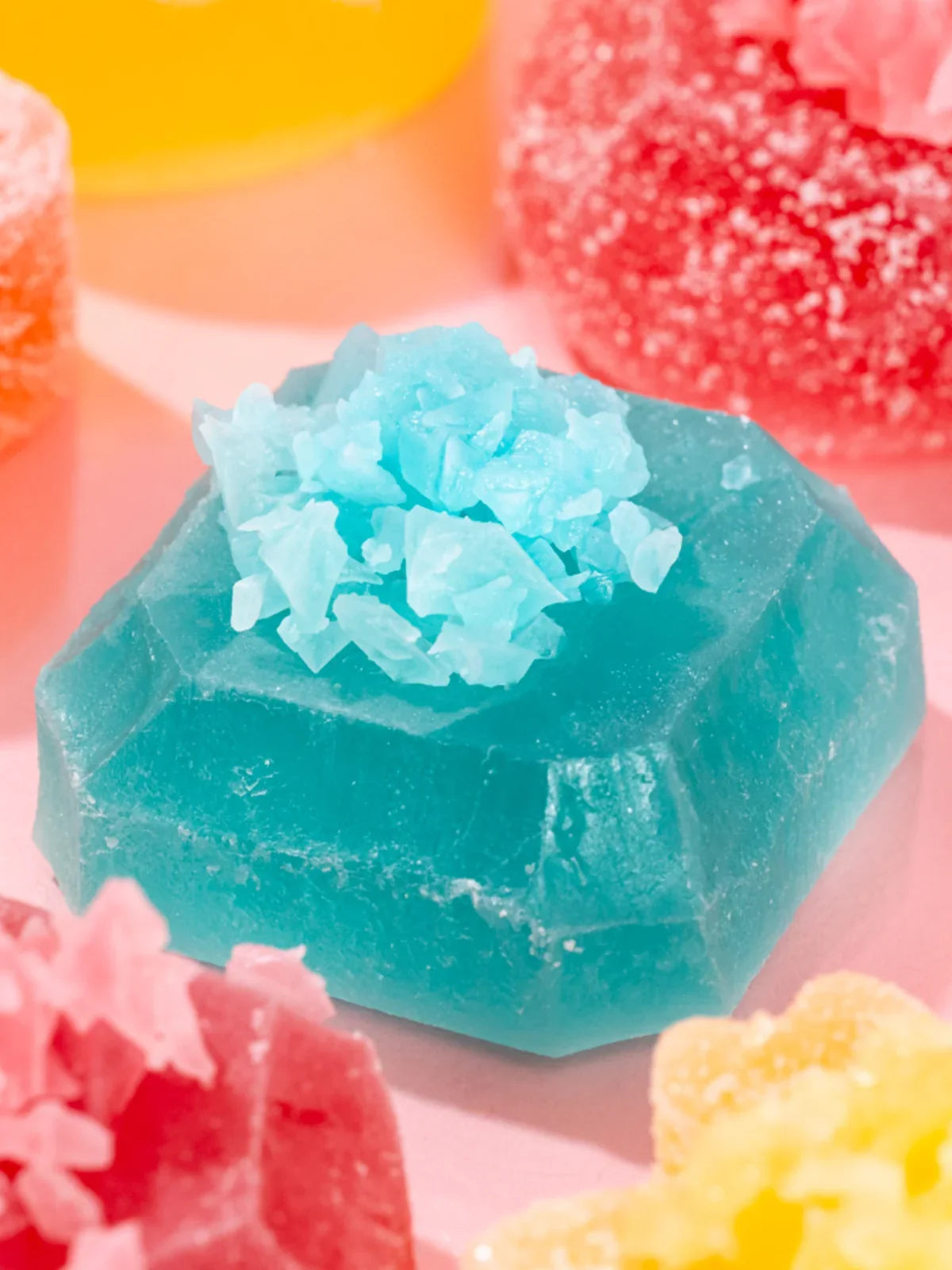 Crystal-like blue object with pink and yellow objects in the background