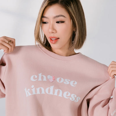Woman wearing a pink sweatshirt with 'choose kindness' text