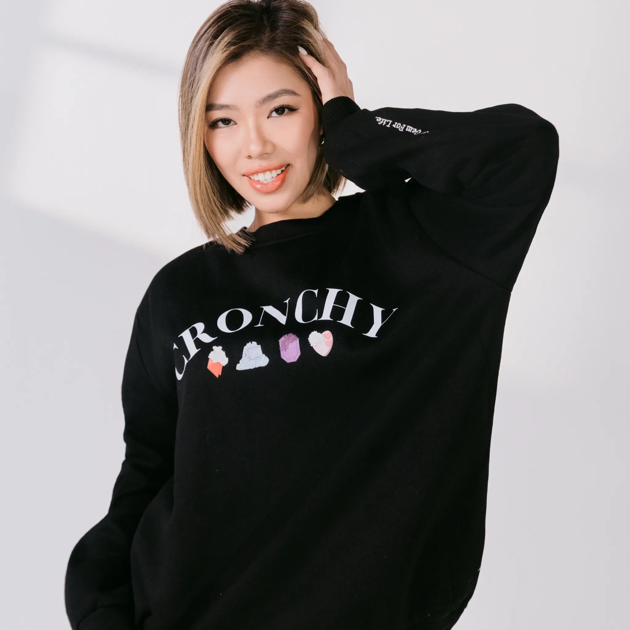 Person wearing a black sweatshirt with colorful graphics and text on a white background