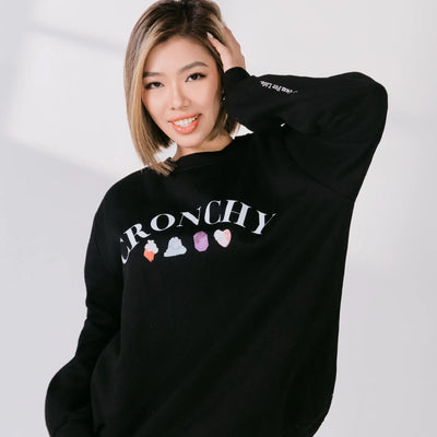 Person wearing a black sweatshirt with colorful graphics and text on a white background