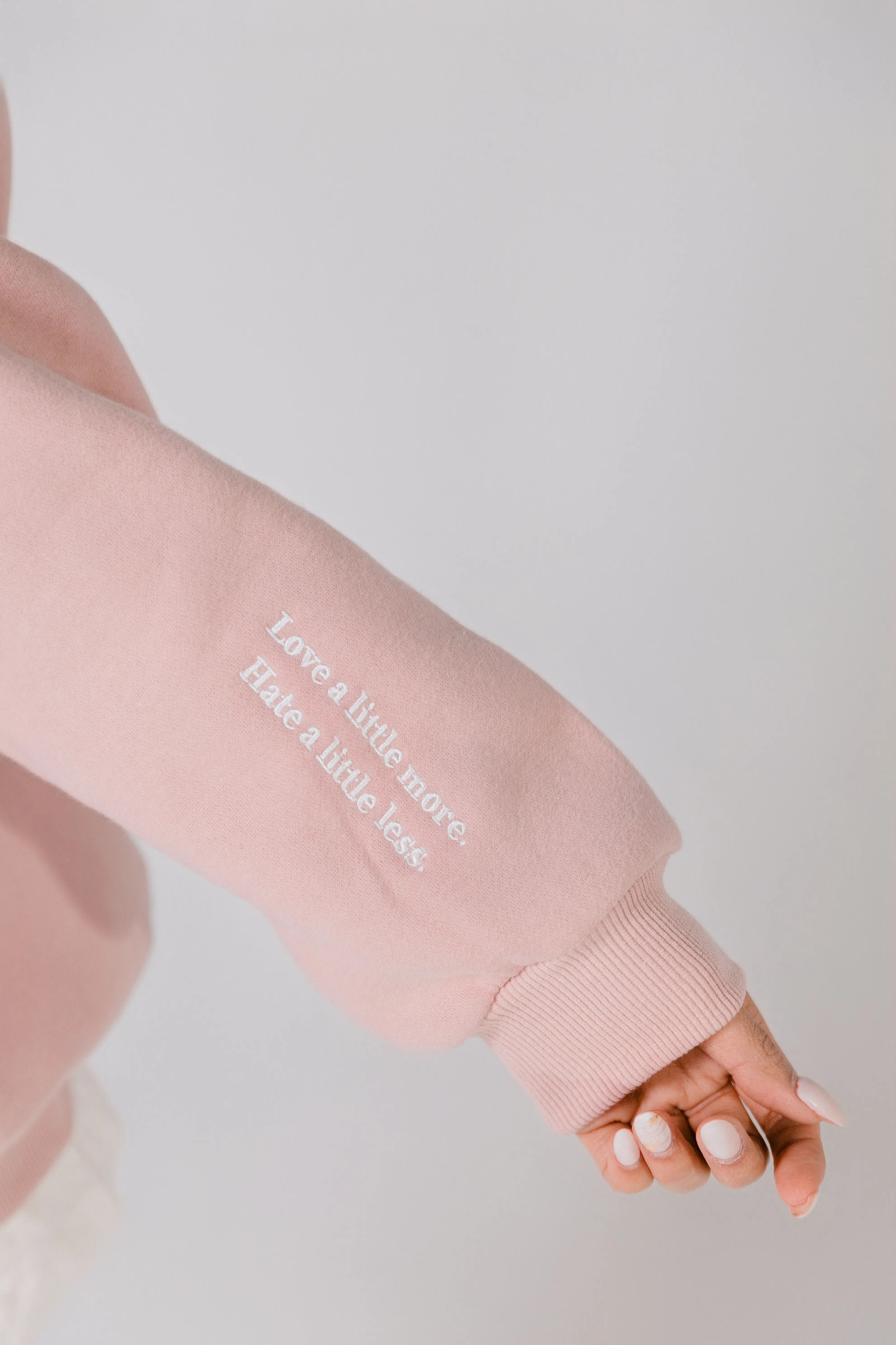 Close-up of sleeve print reading “Love a little more. Hate a little less.”