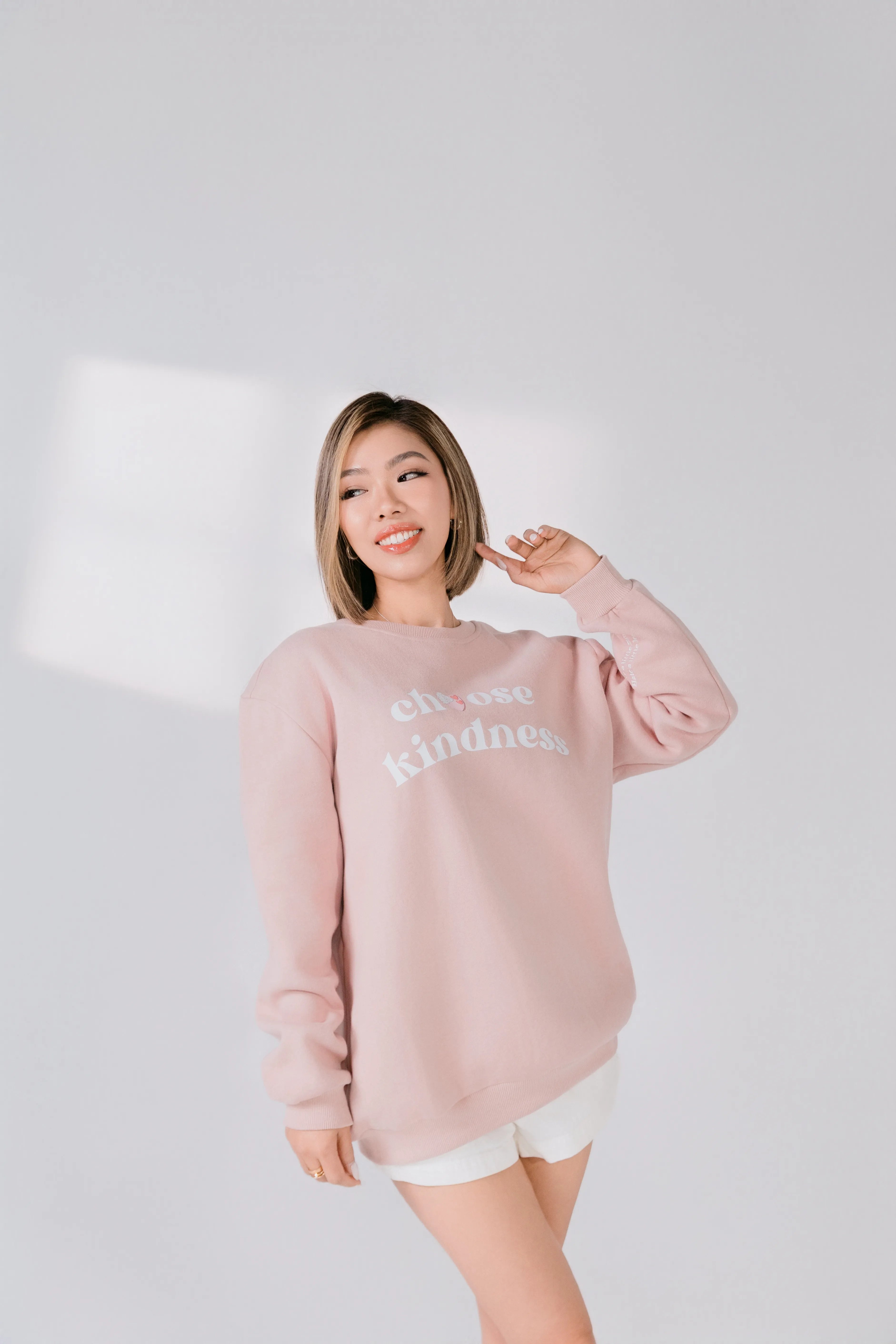 Woman wearing a pink sweatshirt with text on a plain background