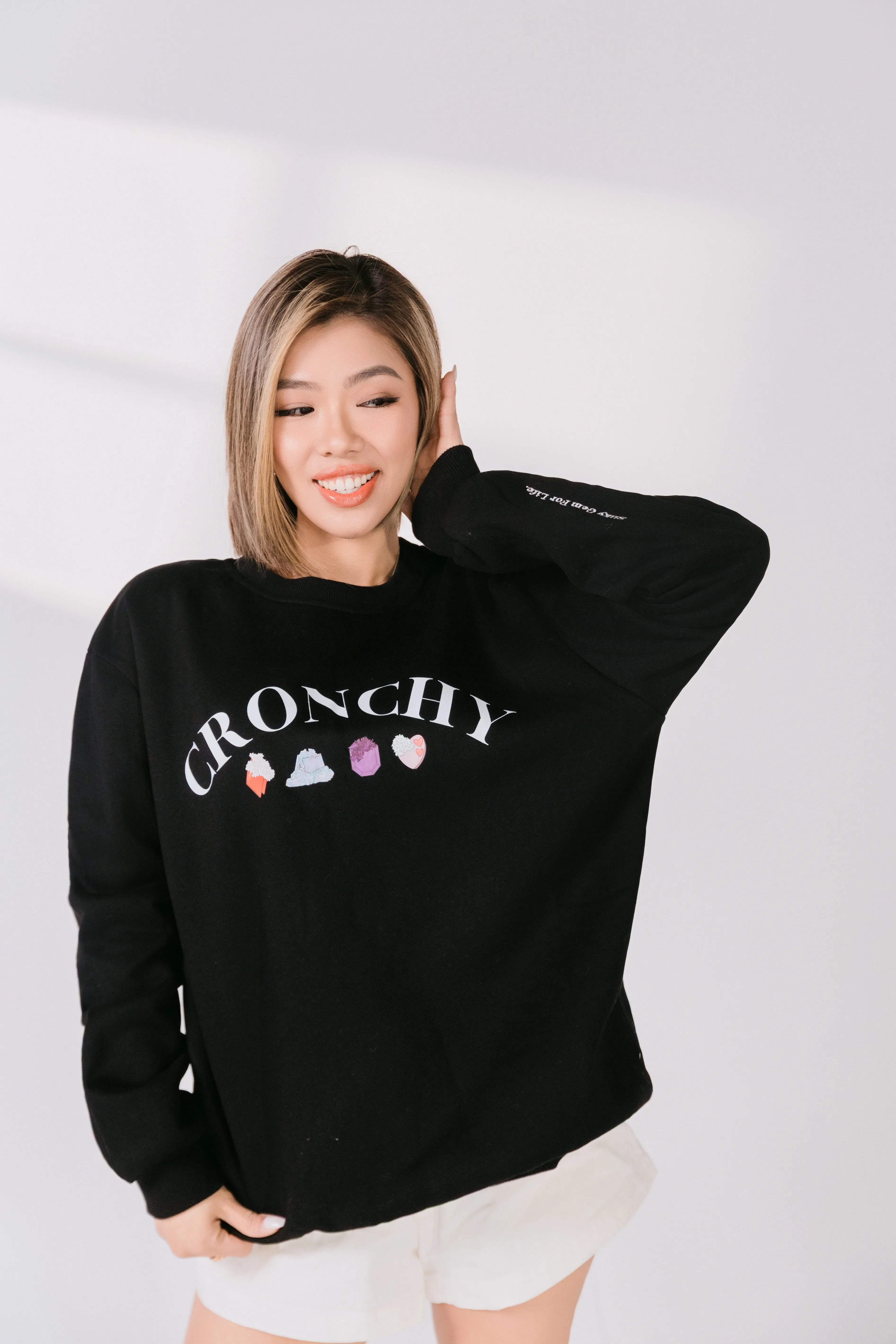 Lifestyle image of model smiling in black candy-inspired sweatshirt.