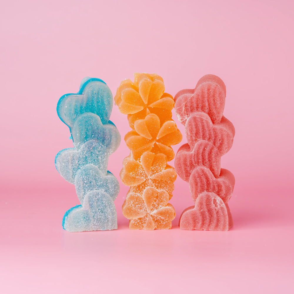 Trio of candies dusted with sour sugar. Bluea heart shape, orange flowers, and red hearts.