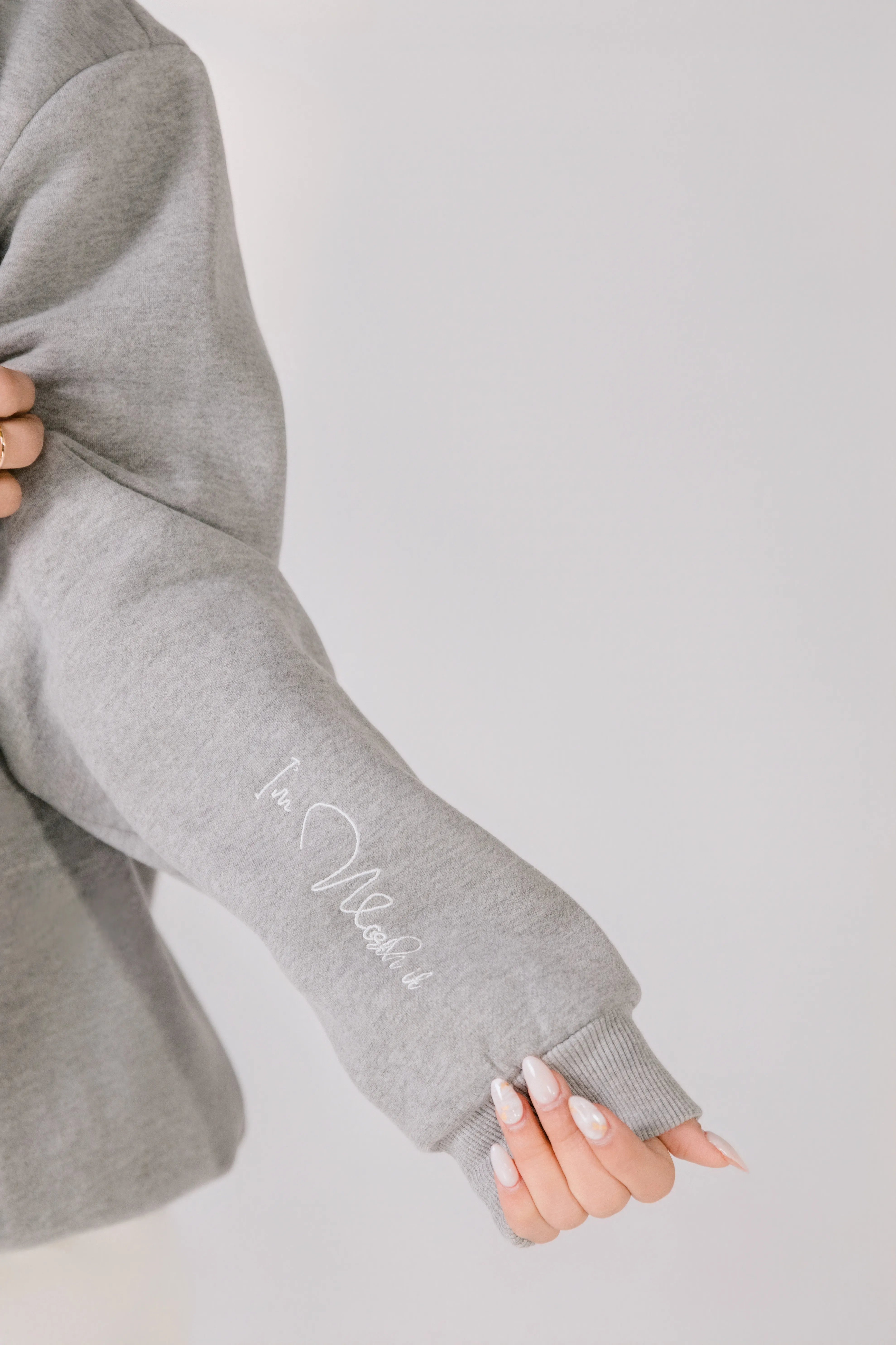 Close-up of white script embroidery on gray cotton poly blend fabric.