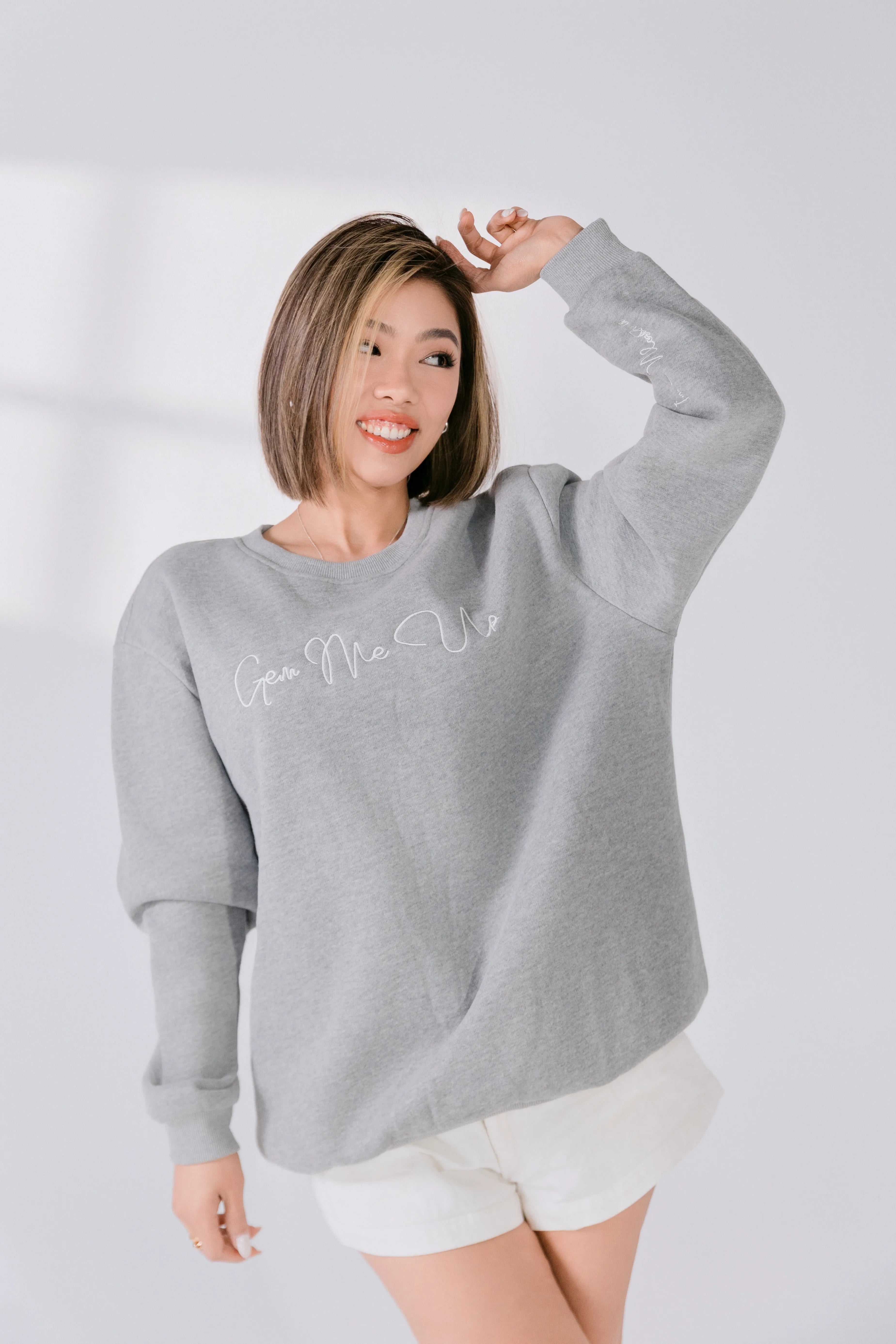 Lifestyle image of model smiling in gray sweatshirt.
