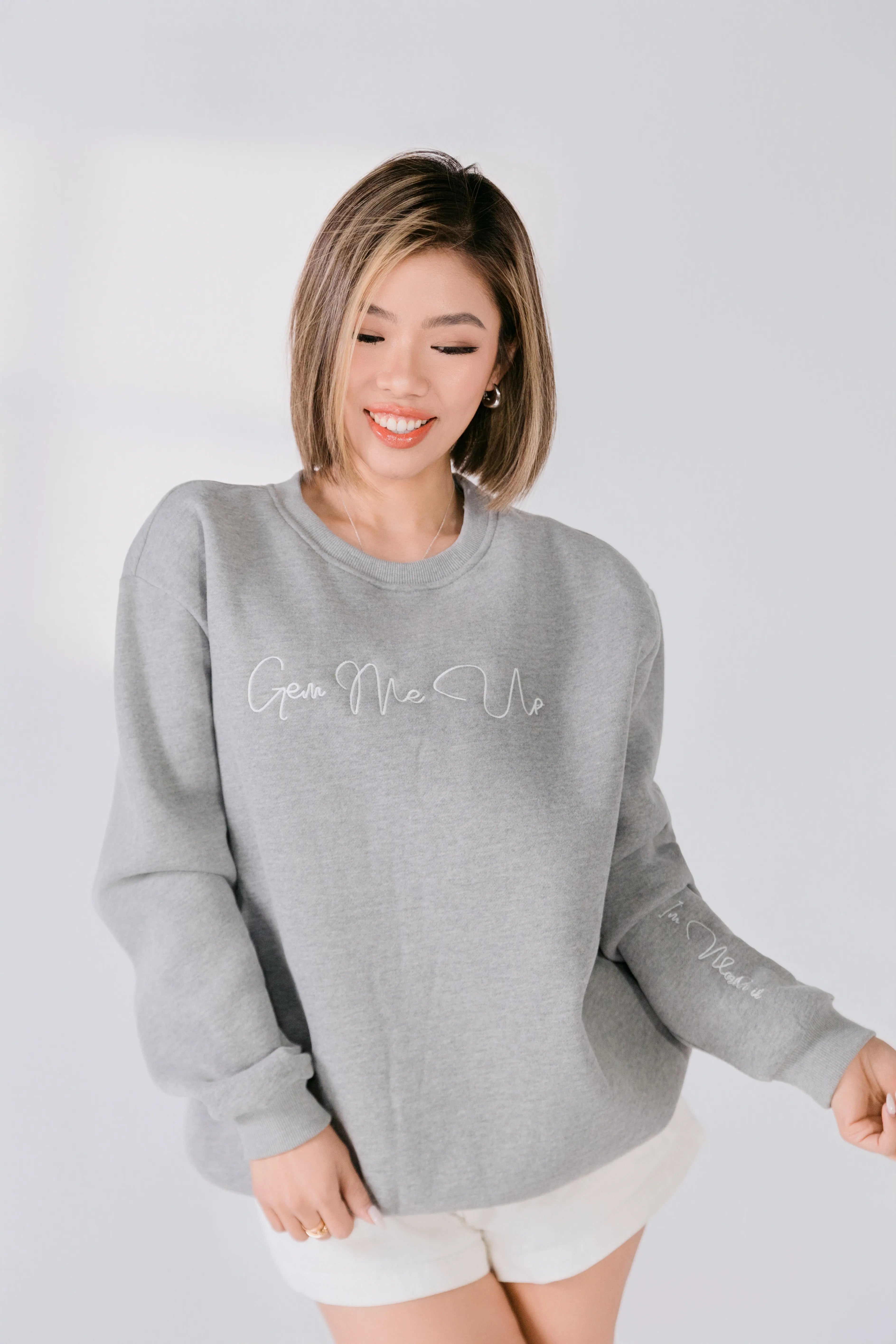 Woman wearing a gray sweatshirt with text on a white background