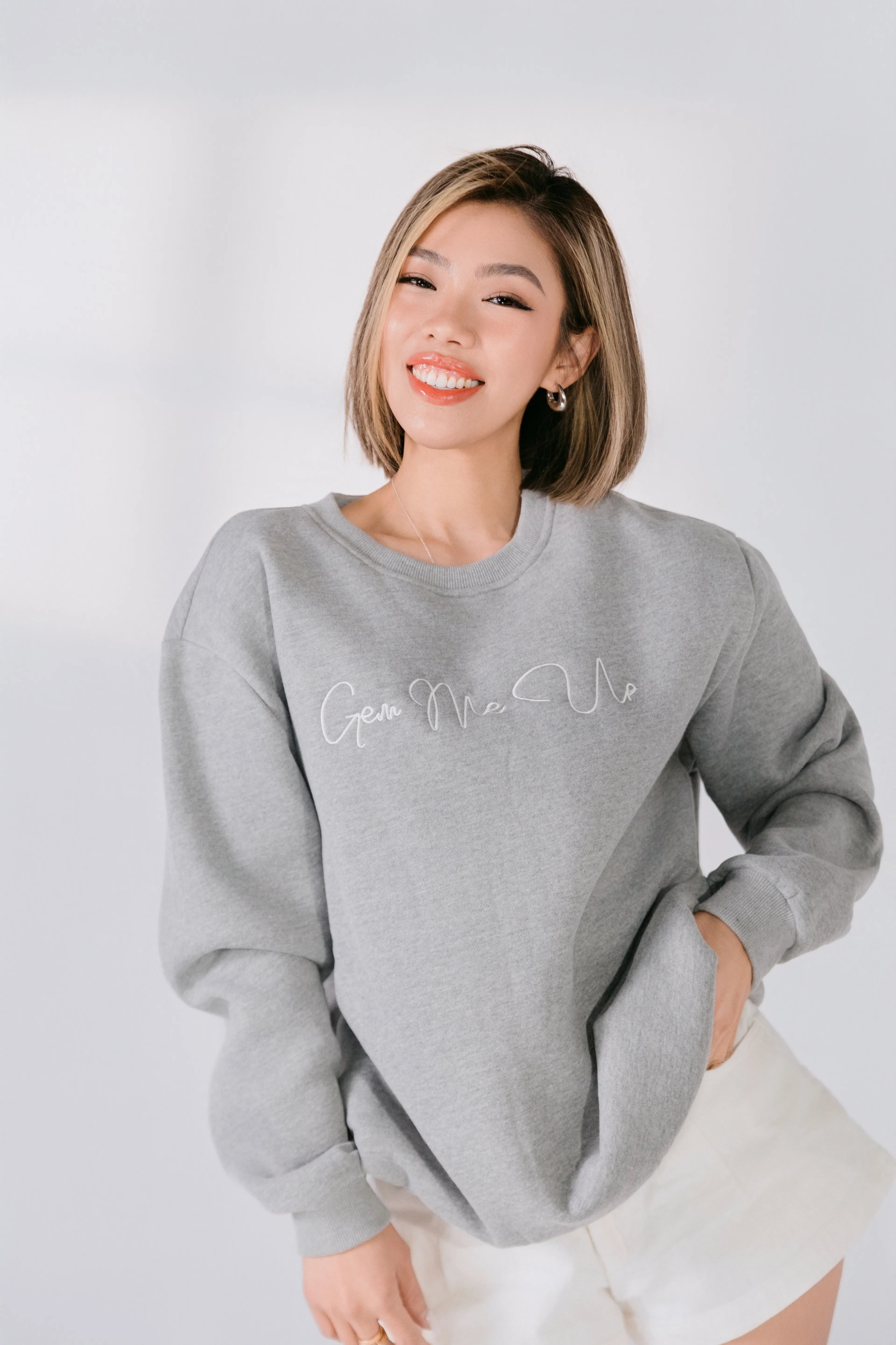 Lifestyle image of model smiling in gray sweatshirt.