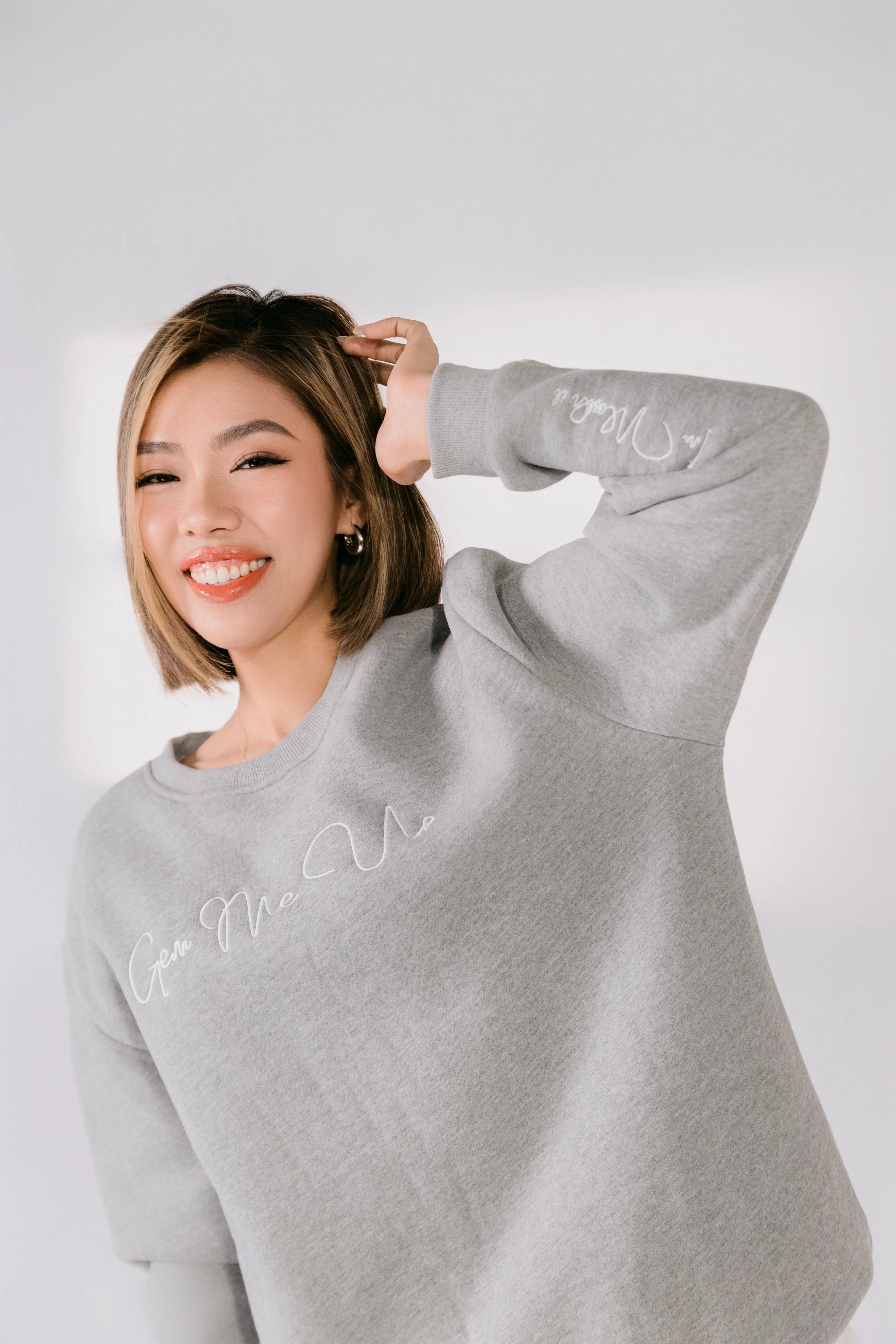 Model wearing heather gray “Gem Me Up” embroidered crewneck sweatshirt.