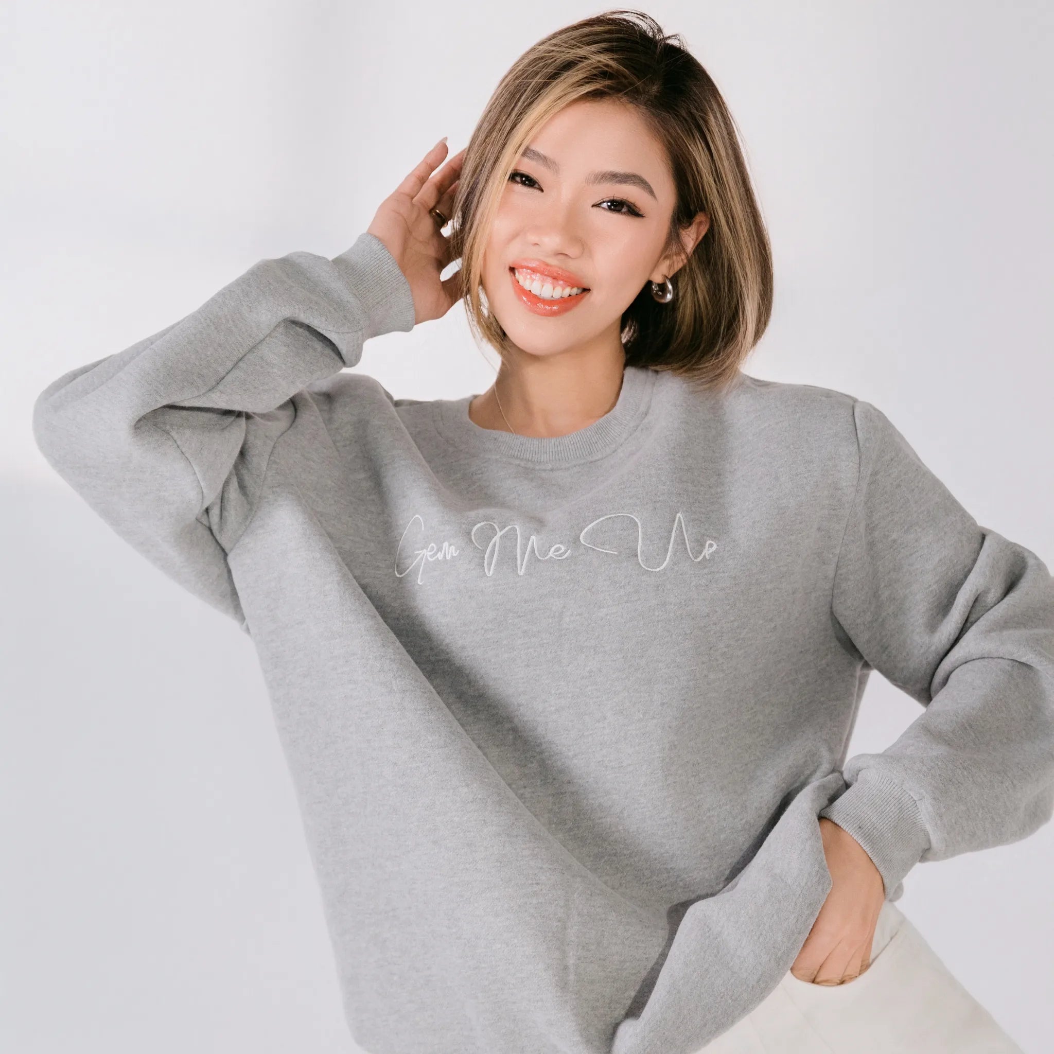 Woman wearing a gray sweatshirt with text on a white background