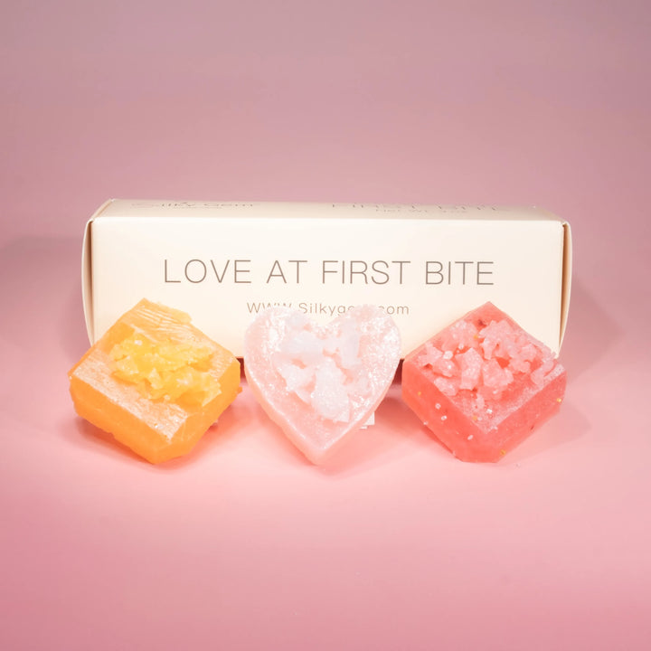 Silkylicious candy cubes with a box labeled 'Love at First Bite' on a pink background