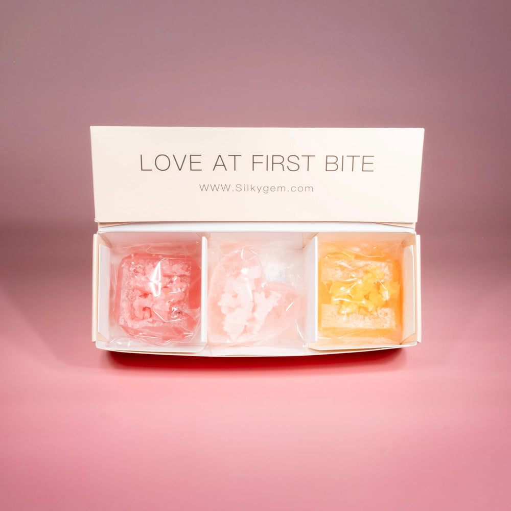 Three Love at First Bite crystal candies displayed on a pink background