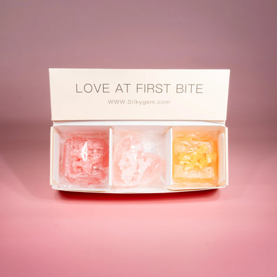 Three Love at First Bite crystal candies displayed on a pink background