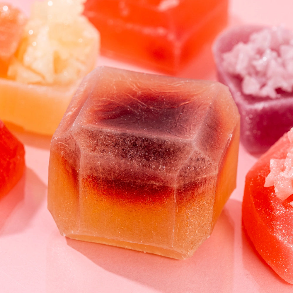Close-up of a gradient, hexagonal Silky Gem crystal candy from the Love at First Bite collection on a pink background