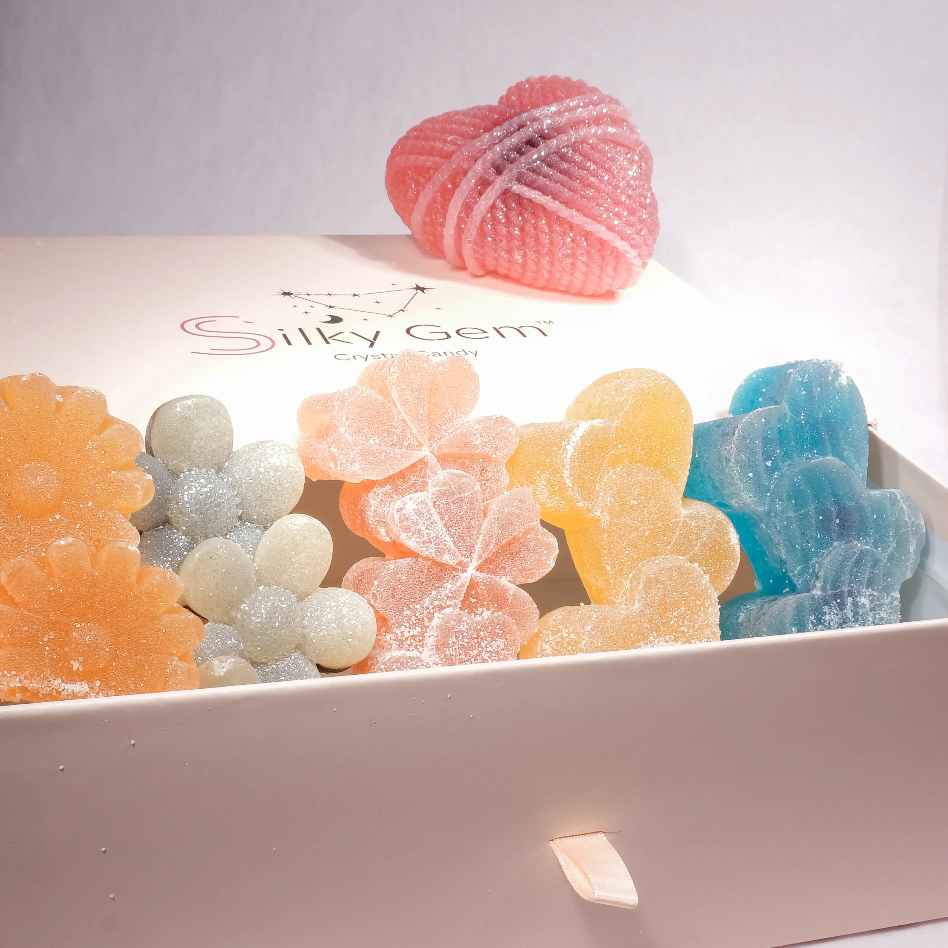 Colorful gummy candies in a box with 'Silky Gem' branding.