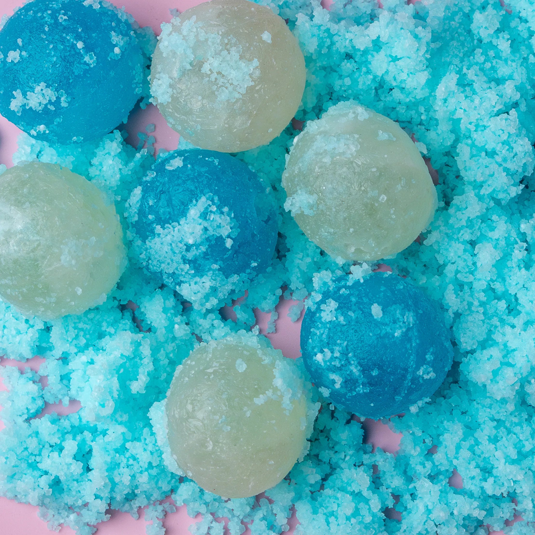 Close-up of blue and green bath bombs on a blue and pink bath bomb base.