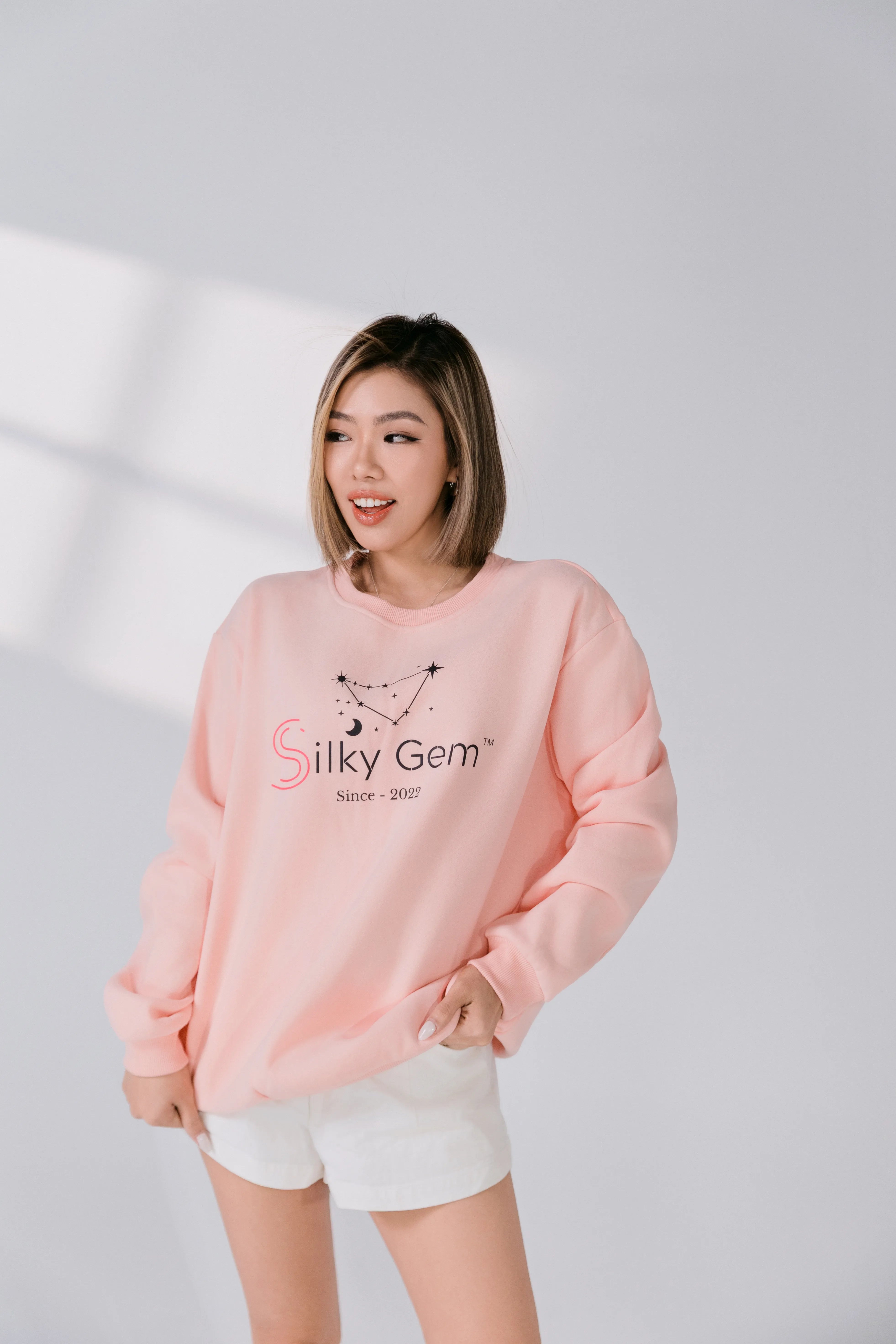 Three-quarter view of blush pink logo sweatshirt.
