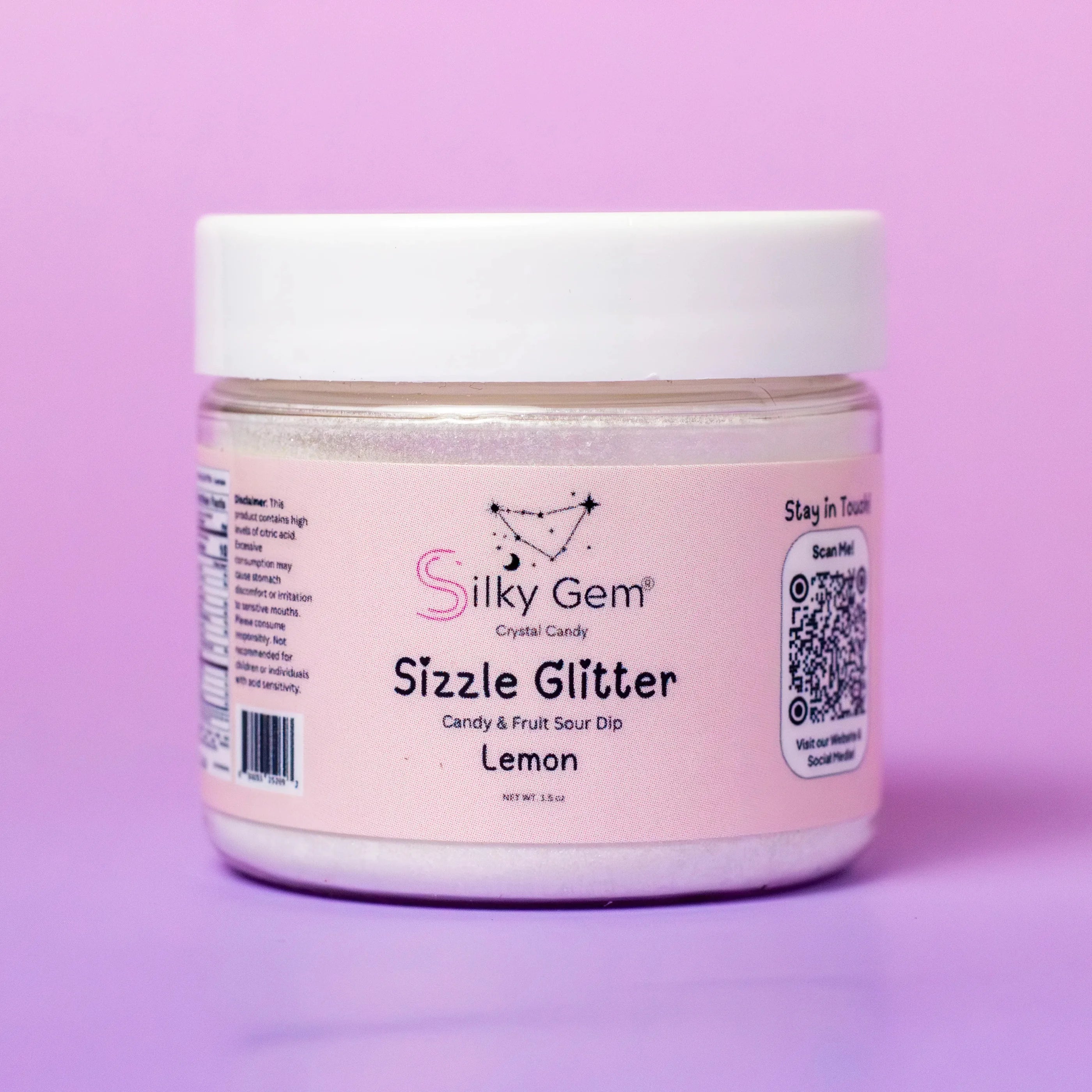 A container of Silky Gem Sizzle Sour Dip Lemon with a pink label, white background, and visible glitter throughout.