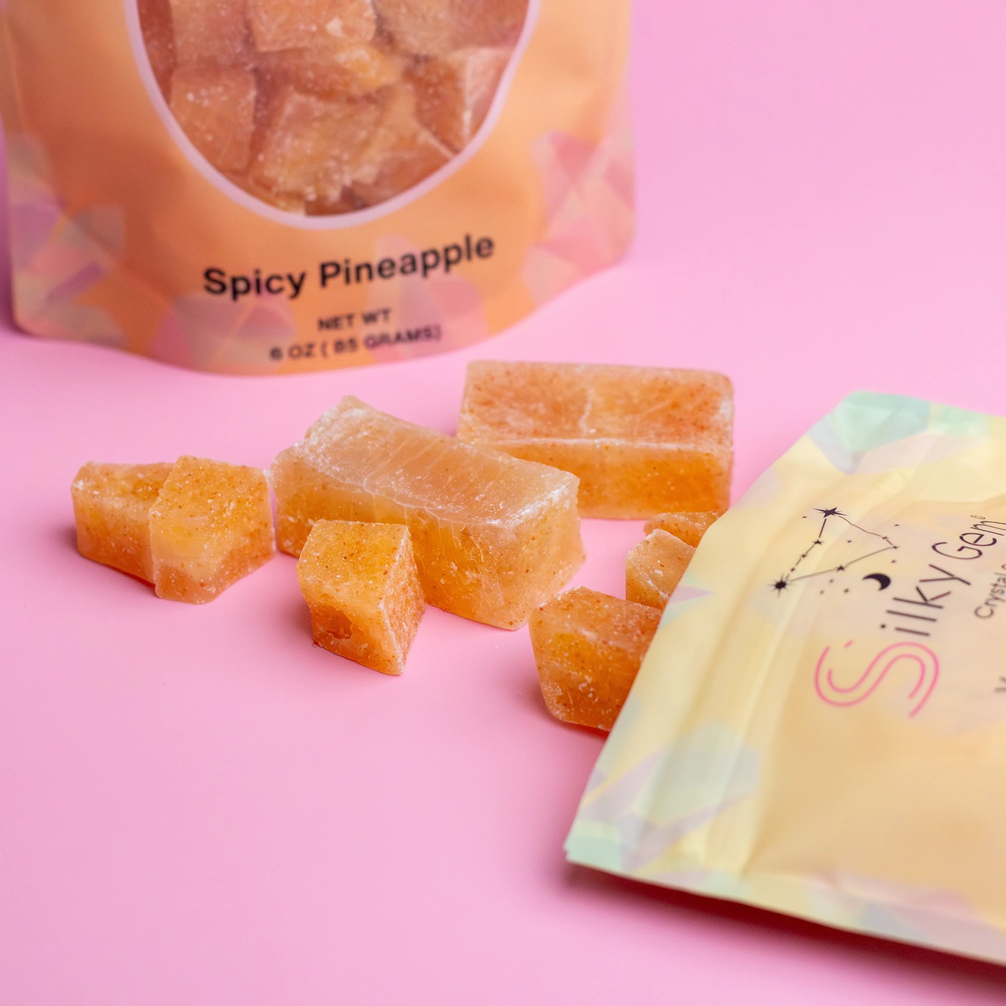 Spicy pineapple gummies with a 'Silky Sens' branded bag on a pink background