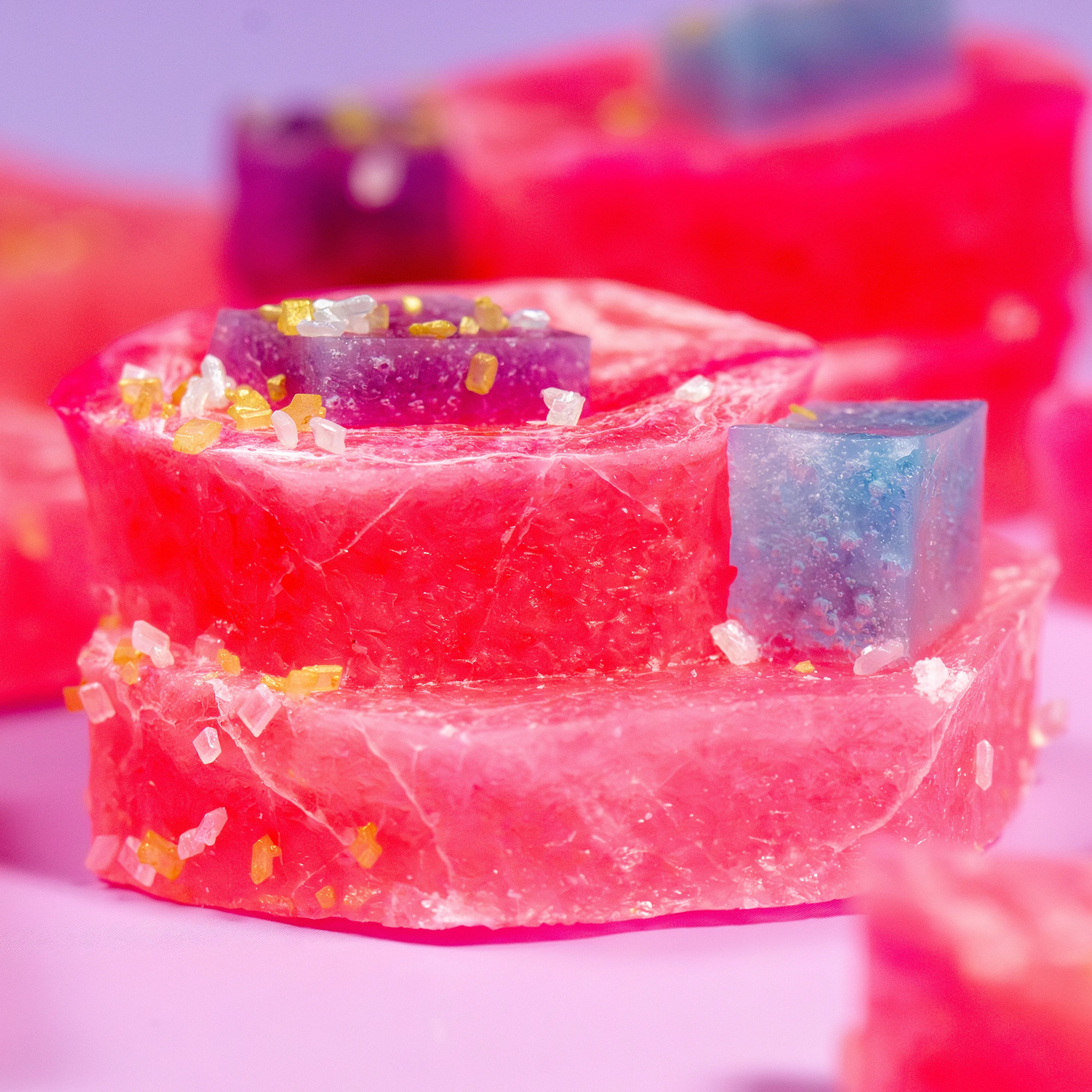 Colorful soap bars with glitter on a pink background
