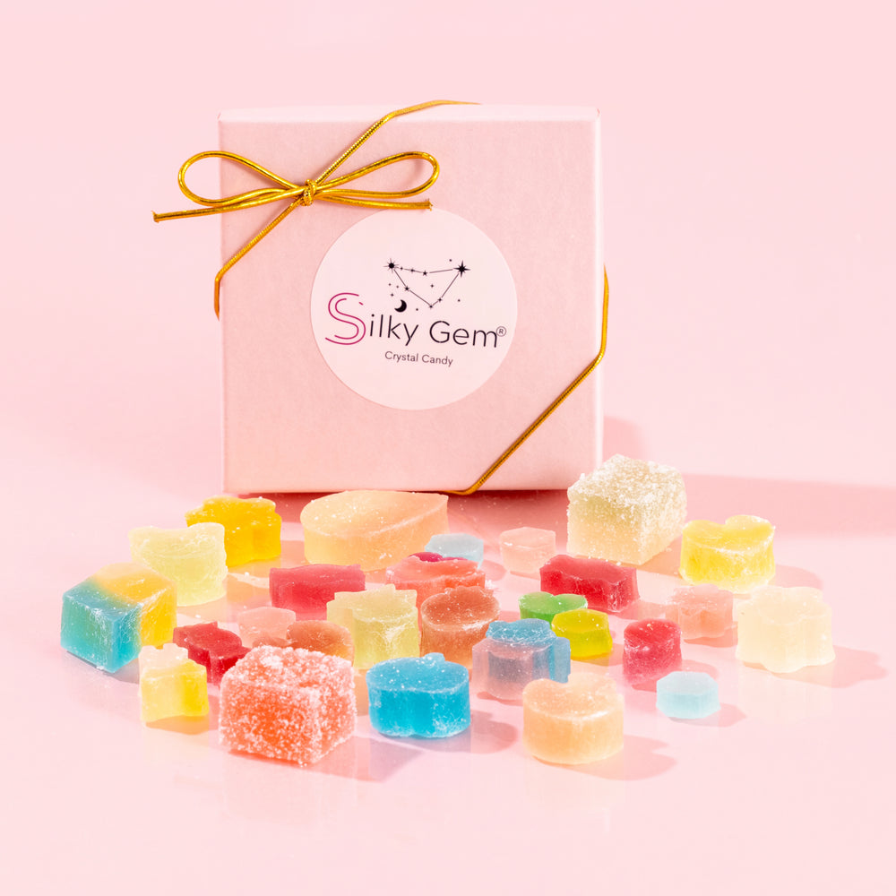Silky Gem Sweethearts Crystal Box featuring an assortment of handcrafted crystal candy pieces and a gold bow on a pink background.