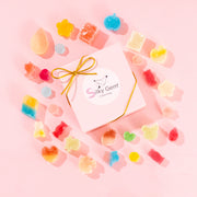 Silky Gem Sweethearts Crystal Box featuring an assortment of handcrafted crystal candy pieces and a gold bow on a pink background