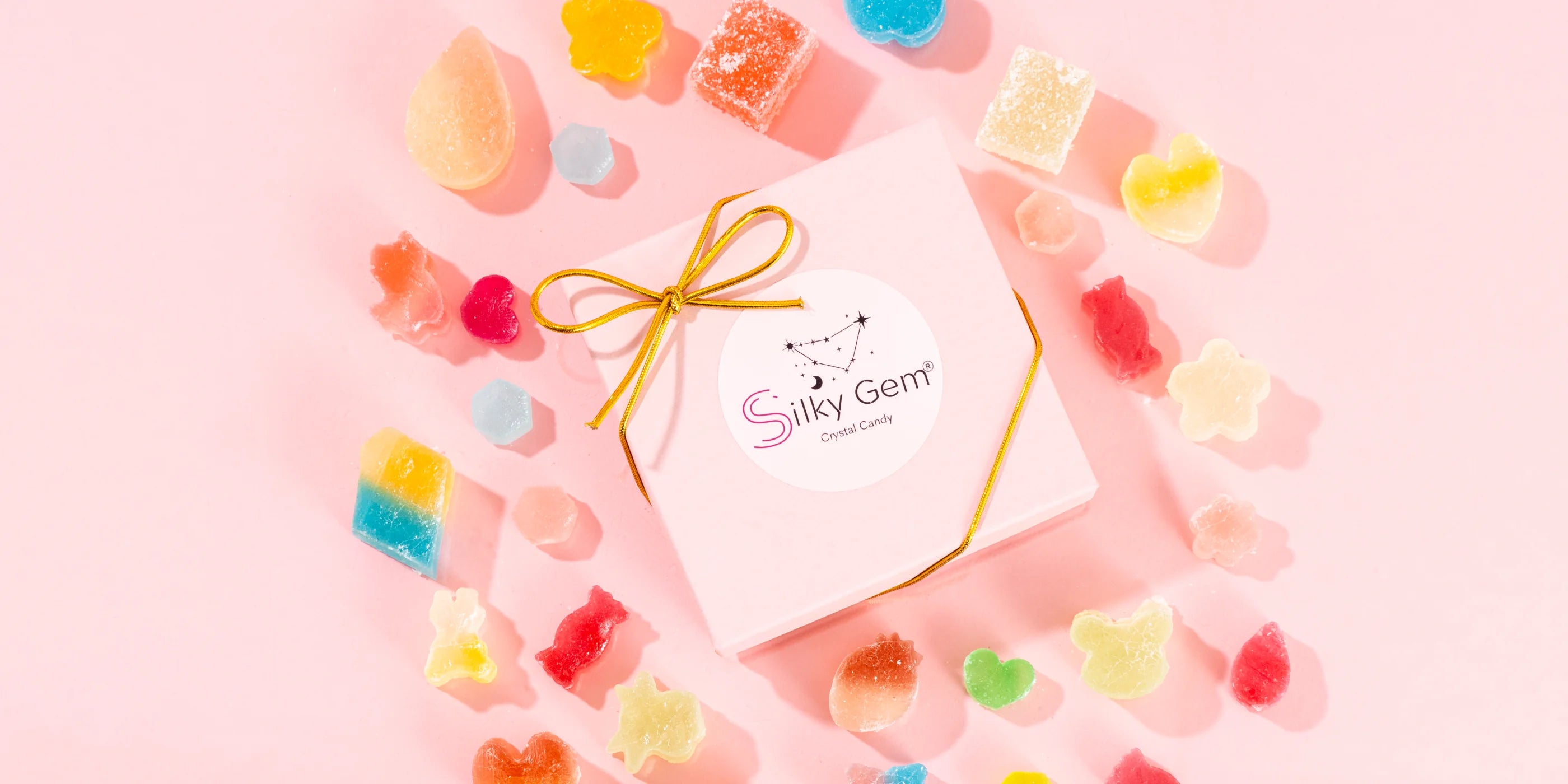 Colorful gummy bears arranged around a pink box with 'Silky Gem' branding on a pink background.