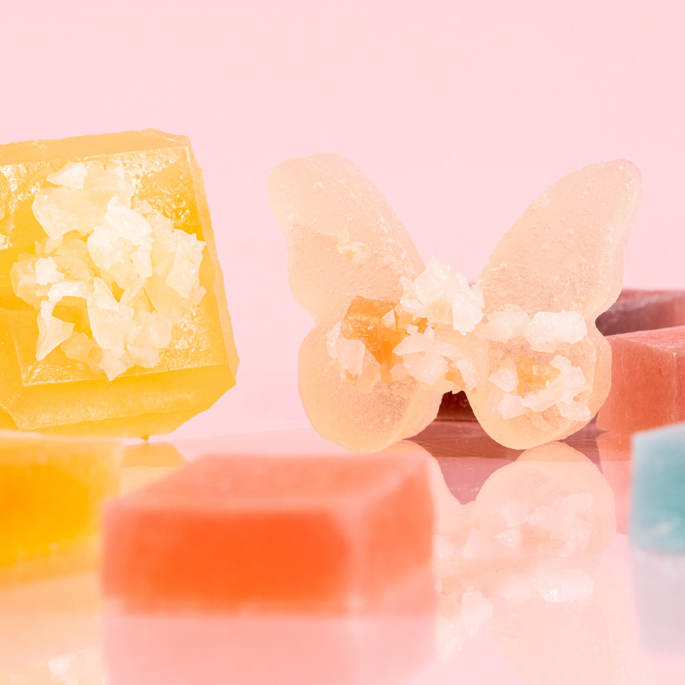 Close-up of assorted butterfly Silky Gem crystal candies from The Gemmies Collection, displayed on a pink background