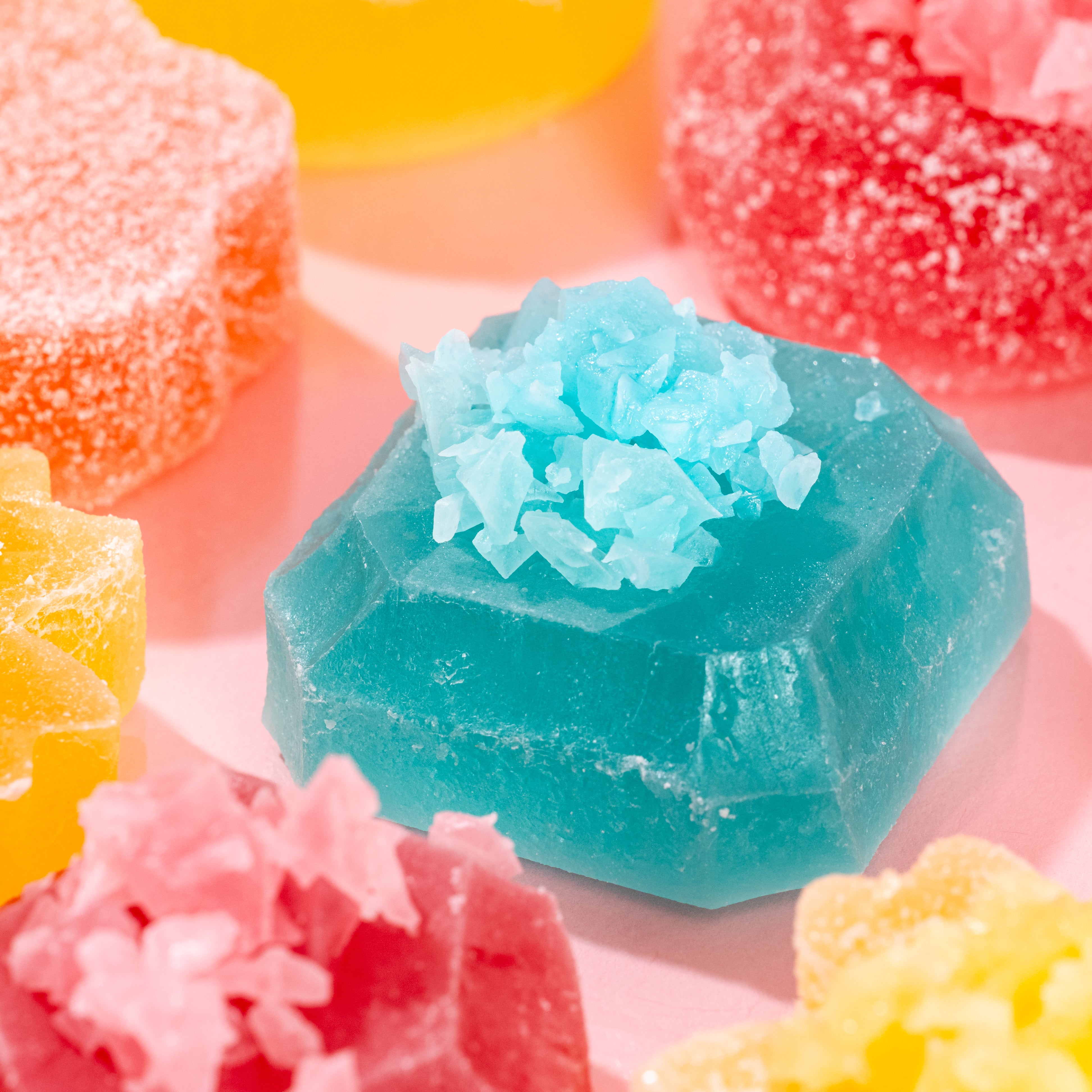 Close-up of vibrant blue Silky Gem crystal candy piece from The Golden Lava collection on a pink background.