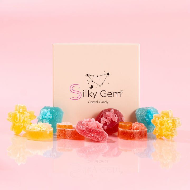 Silky Gem The Golden Lava 9-piece crystal candy collection with sweet and sour gems in a branded box on a pink background.