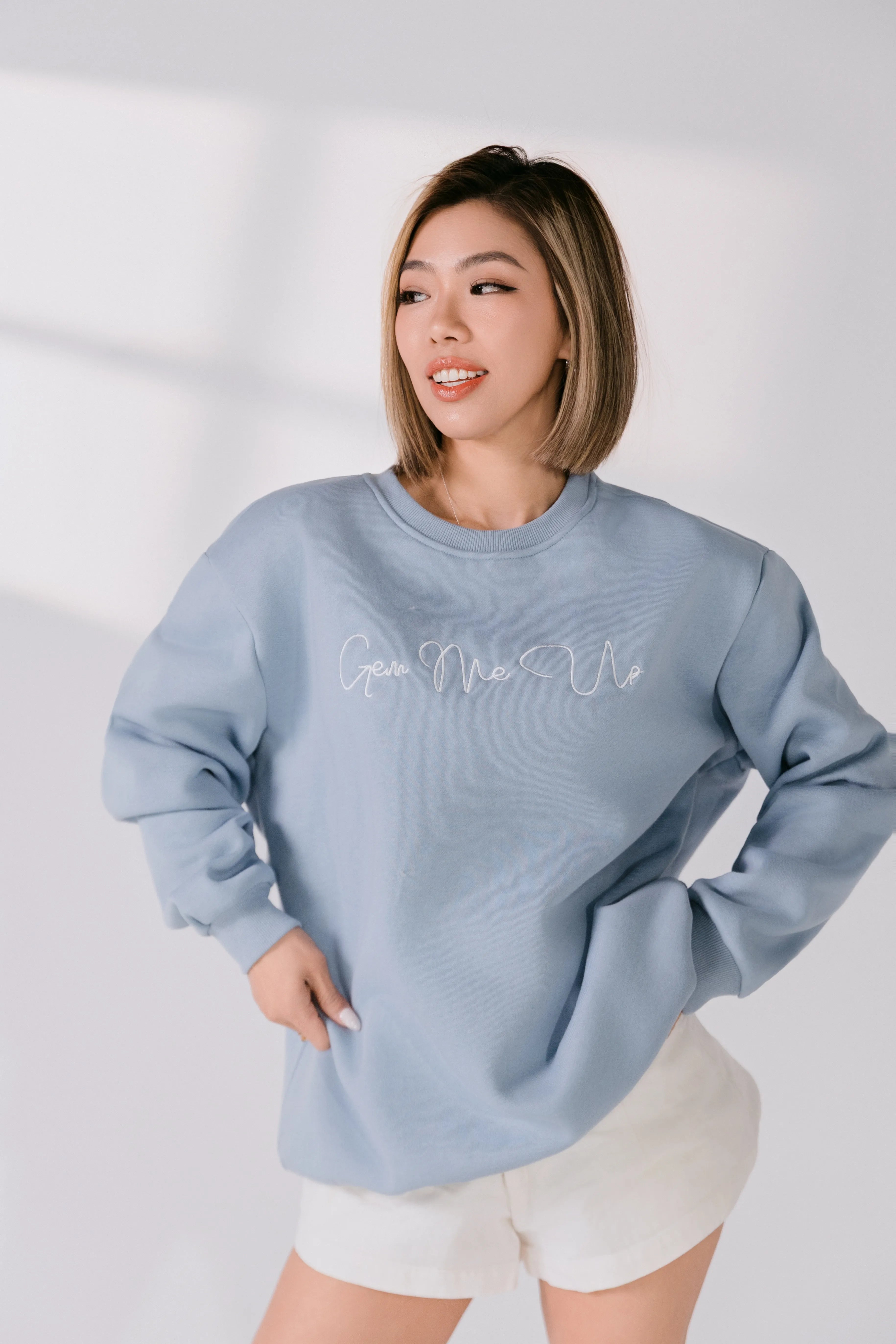 Lifestyle image of model smiling while wearing powder blue sweatshirt.
