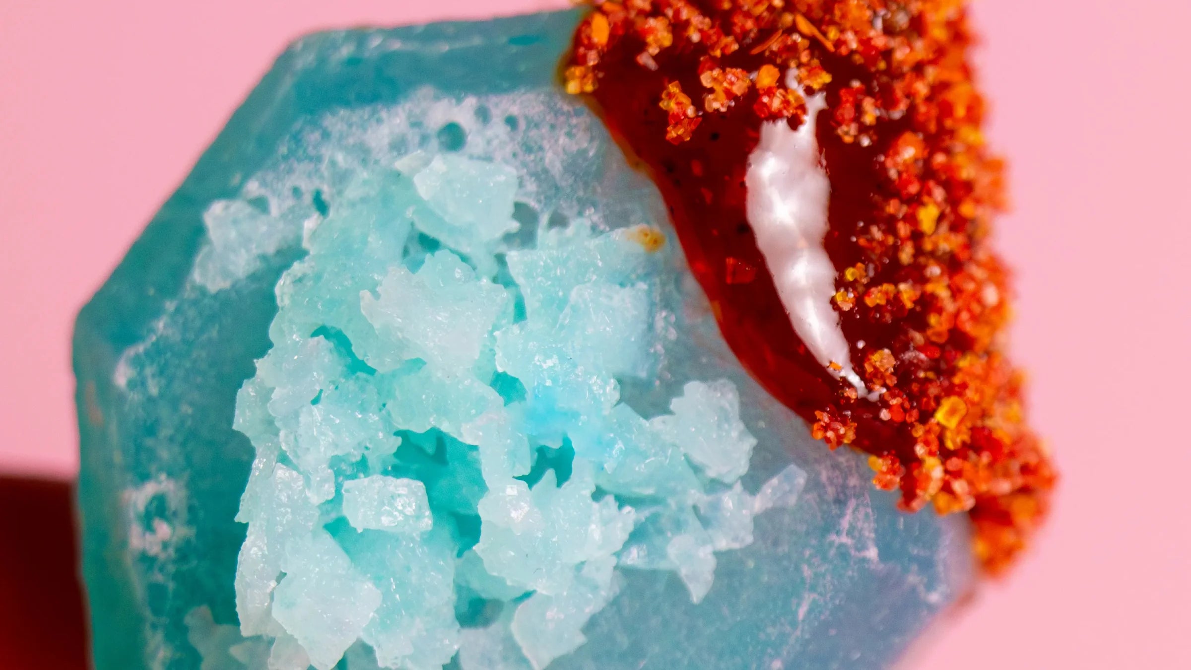 Close-up of a textured blue and red object on a pink background
